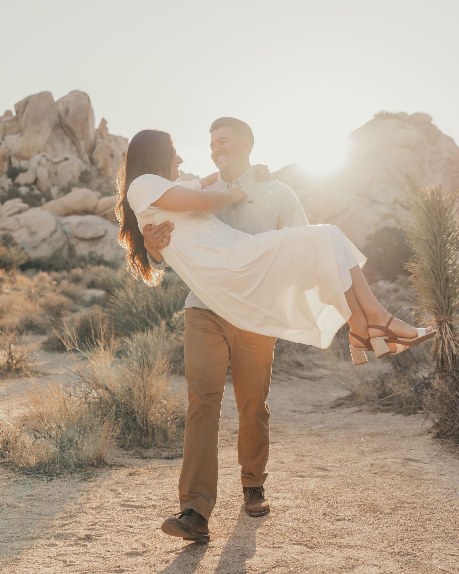 A romantic couple embracing in a desert setting with golden sunlight and rocky formations.