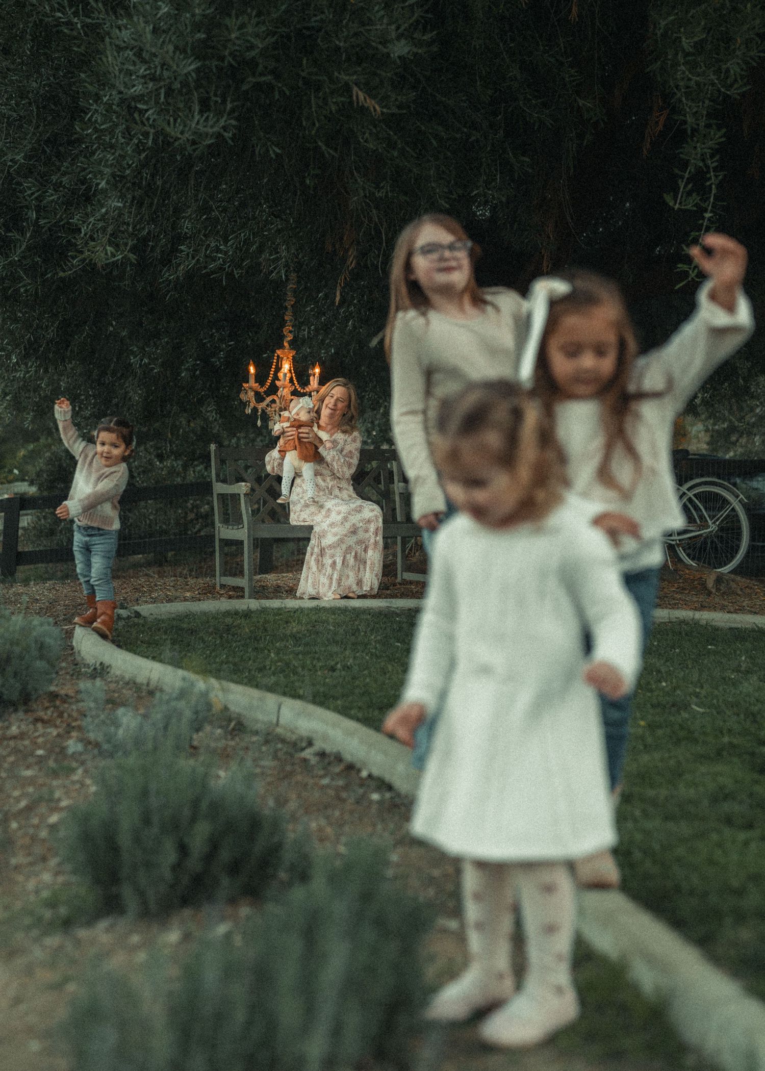 Children playing and jumping with joy outdoors in white outfits during golden hour.