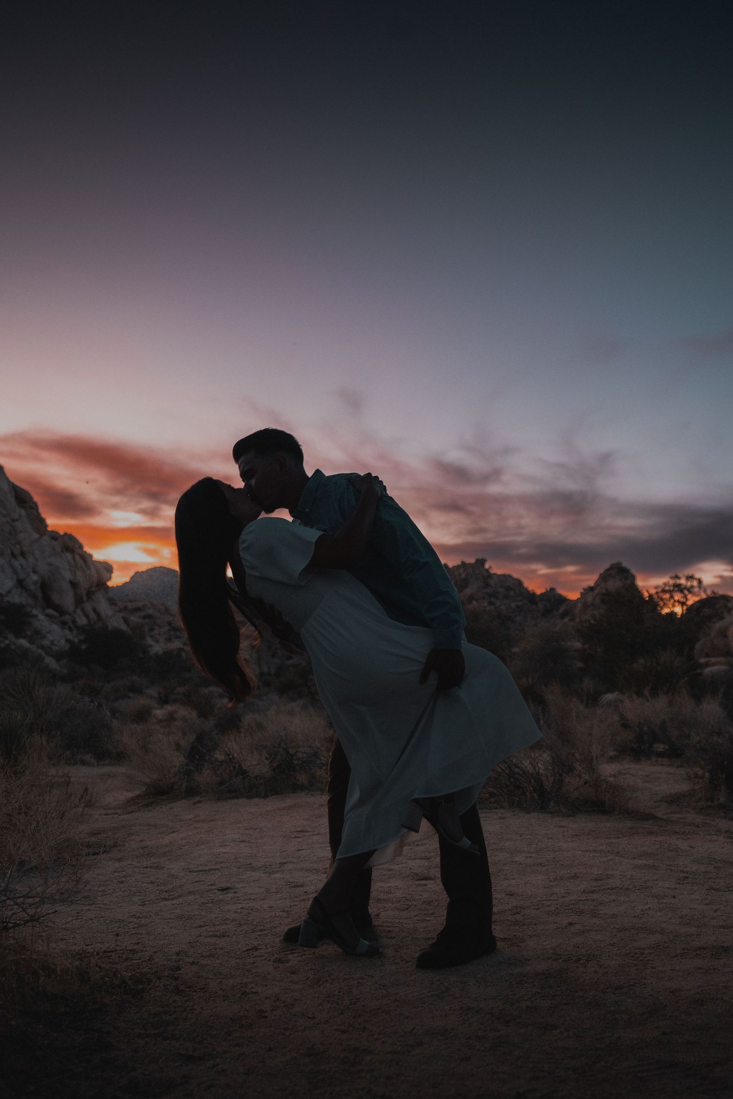 A romantic silhouette of a couple against a desert sunset.