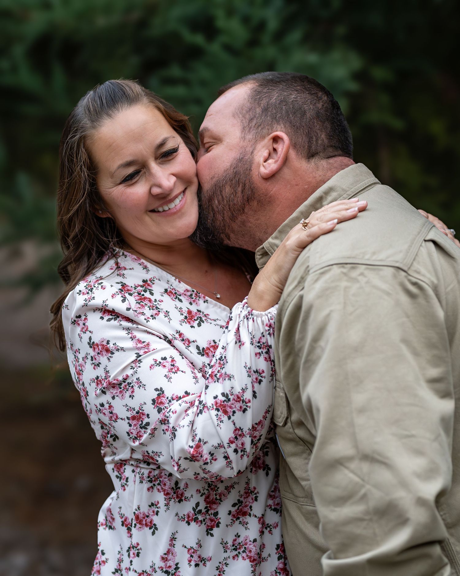 A couple shares an intimate moment outdoors in casual attire.