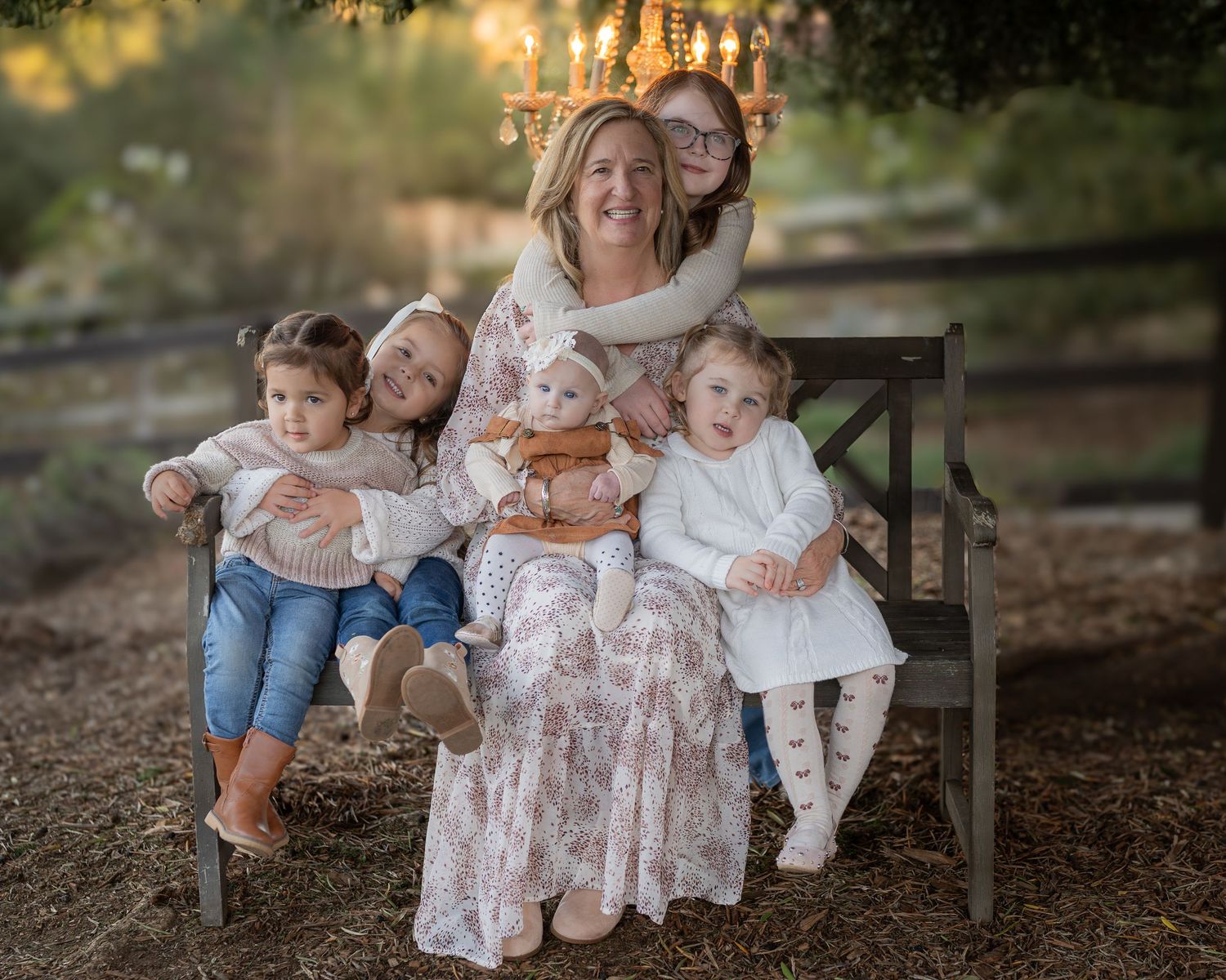 Family members sit together on a wooden bench outdoors during a photo session at sunset.
