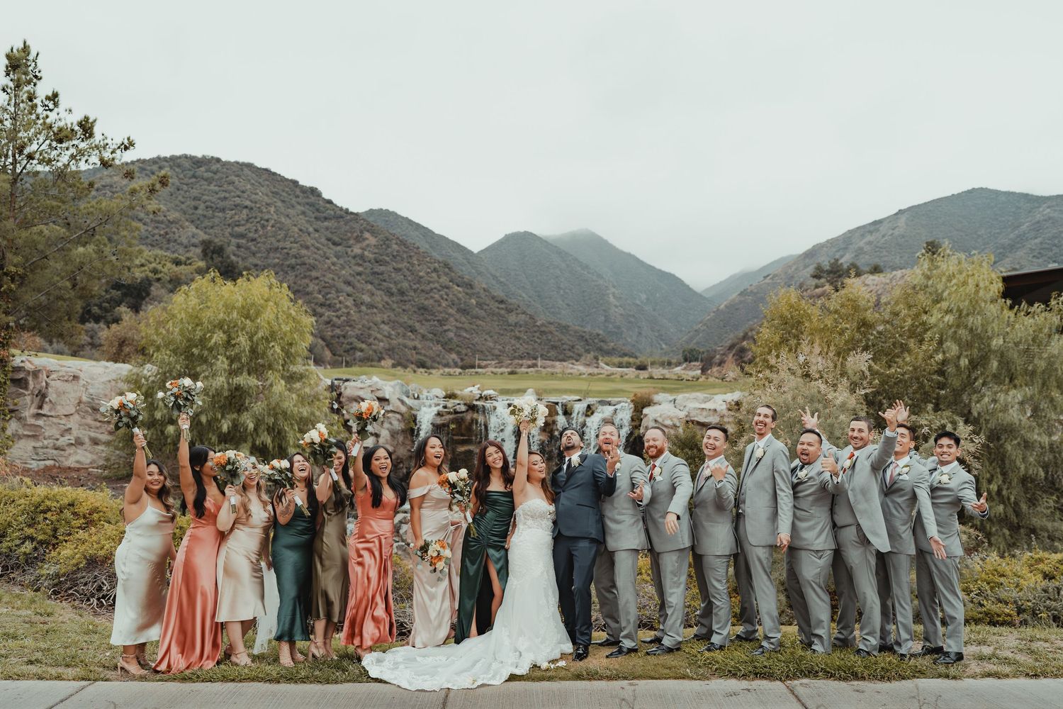 Panoramic wedding party group photo with mountains in the background.