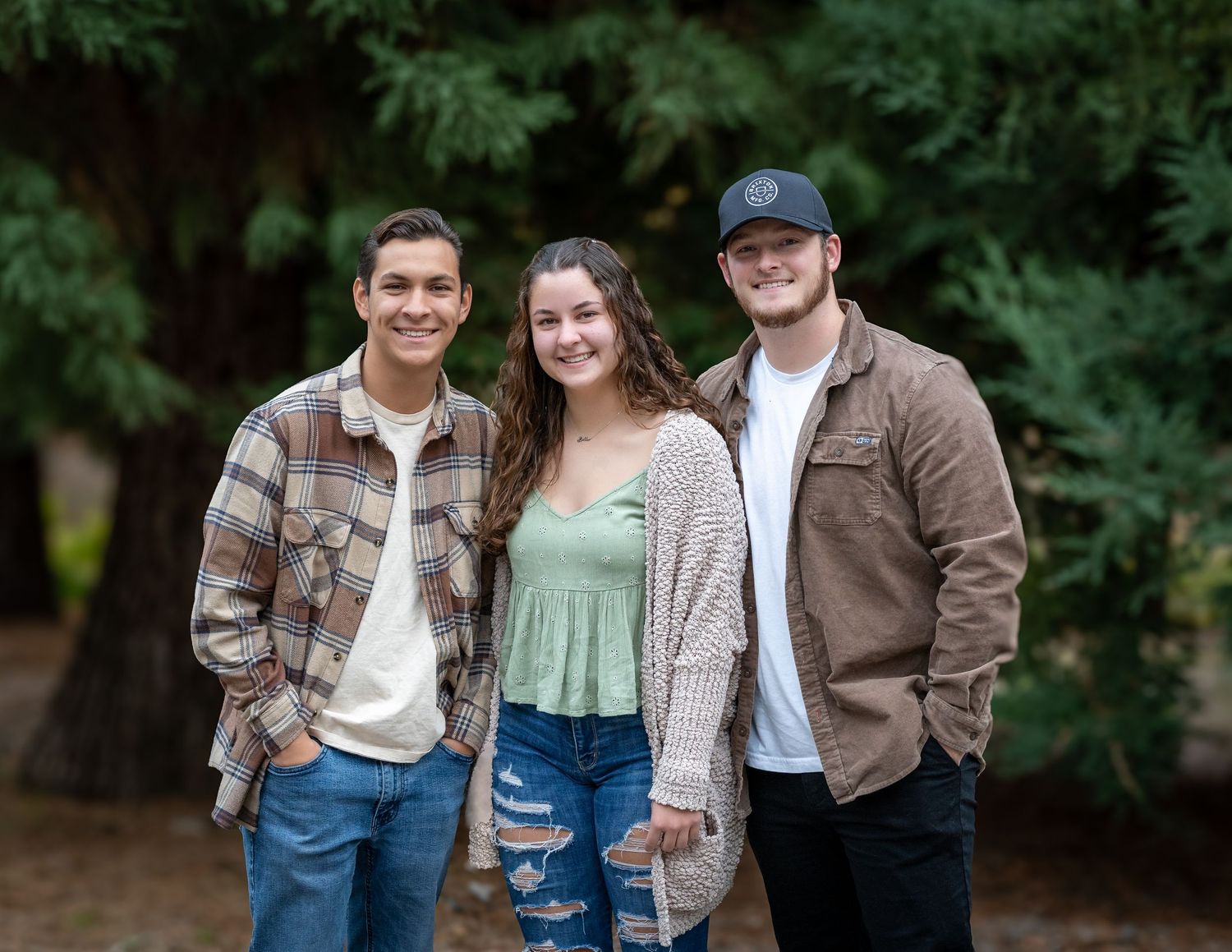 Three people in casual denim and jackets pose together outdoors.