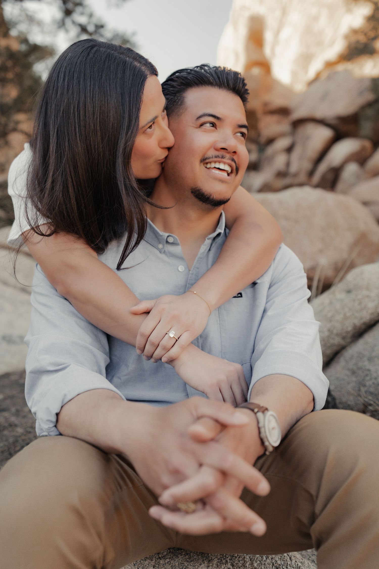 Intimate close-up of a couple sharing tender moments while sitting on desert rocks.