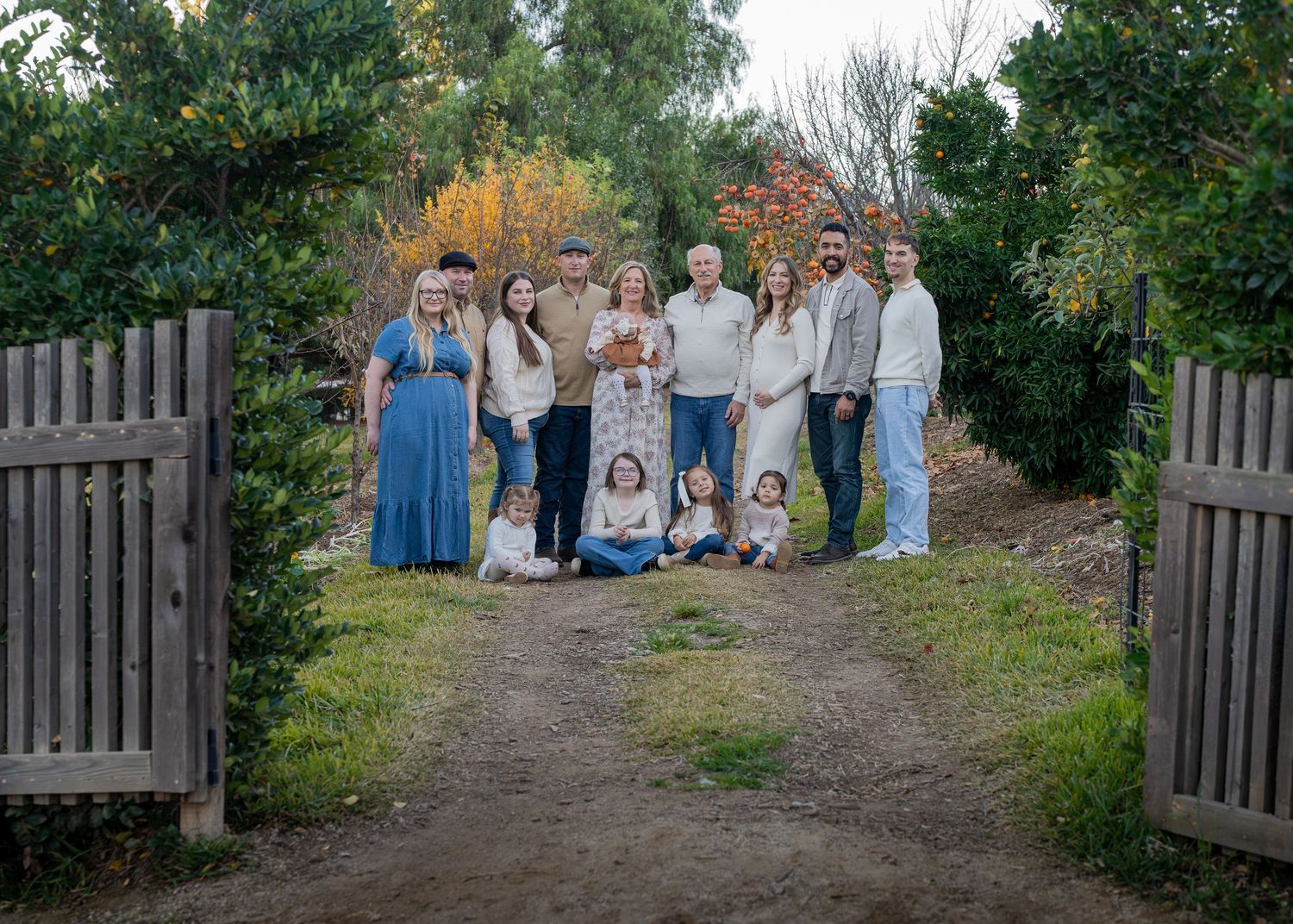 A large family group walks together on a dirt path surrounded by trees.