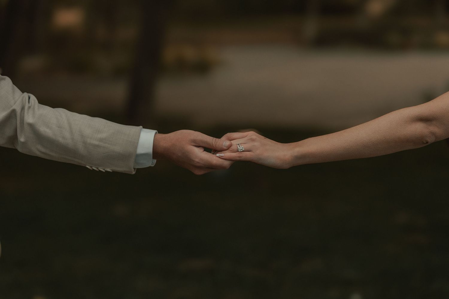 Two hands reaching towards each other with gentle touch against dark blurred background in romantic moment.
