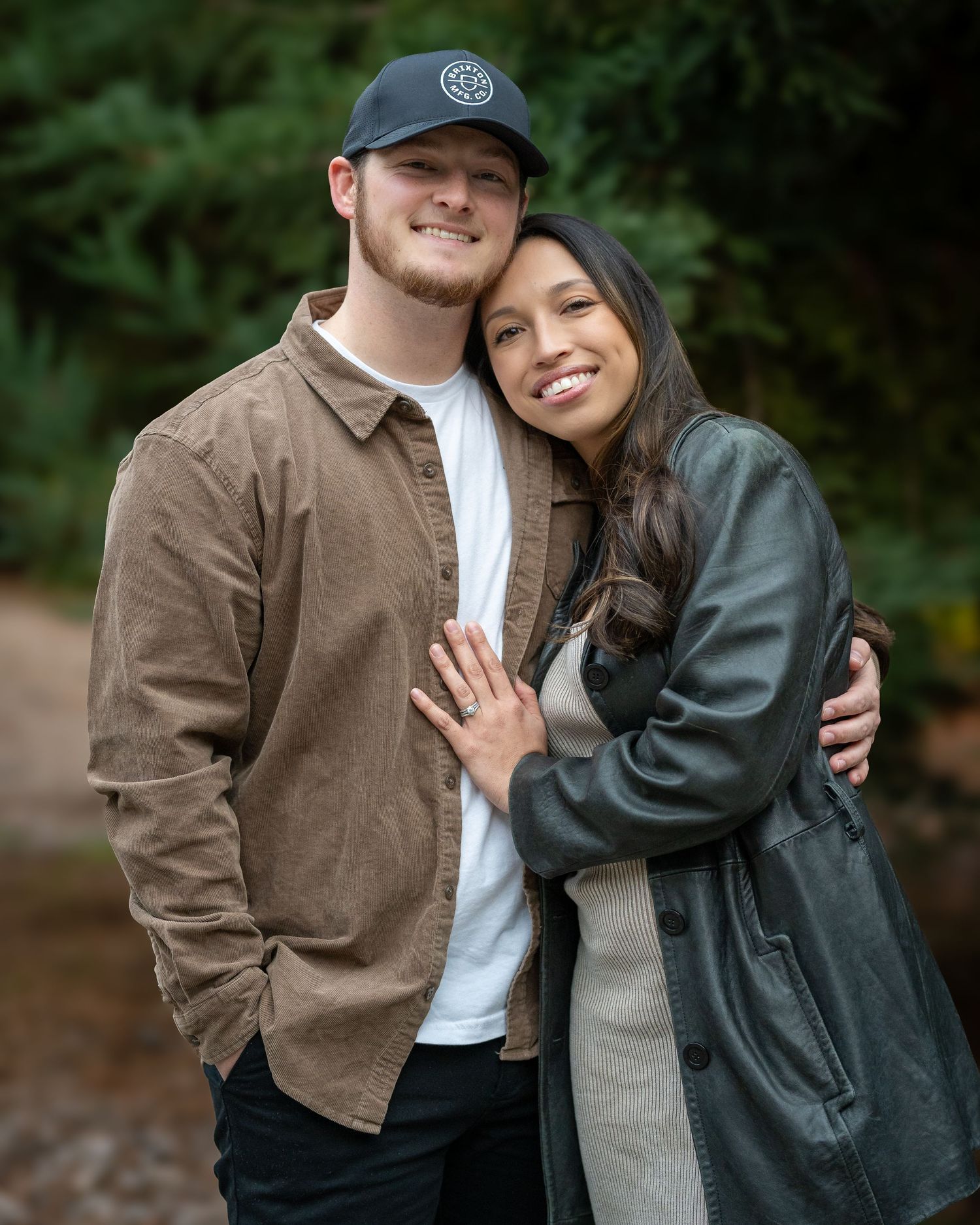A couple embraces while wearing casual jackets in an outdoor setting.