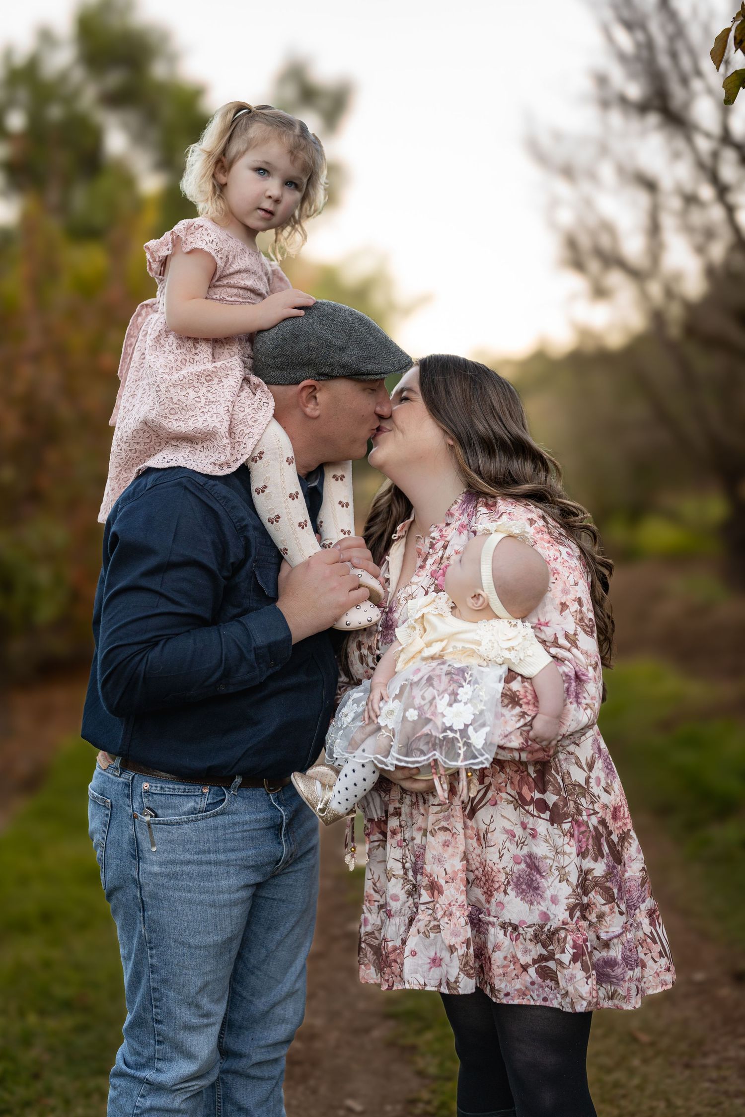 Family with young kids captured during outdoor photo session at sunset.
