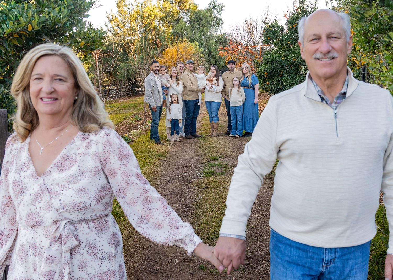 Multi-generational family members spread out in a line outdoors during autumn, wearing coordinated casual attire.