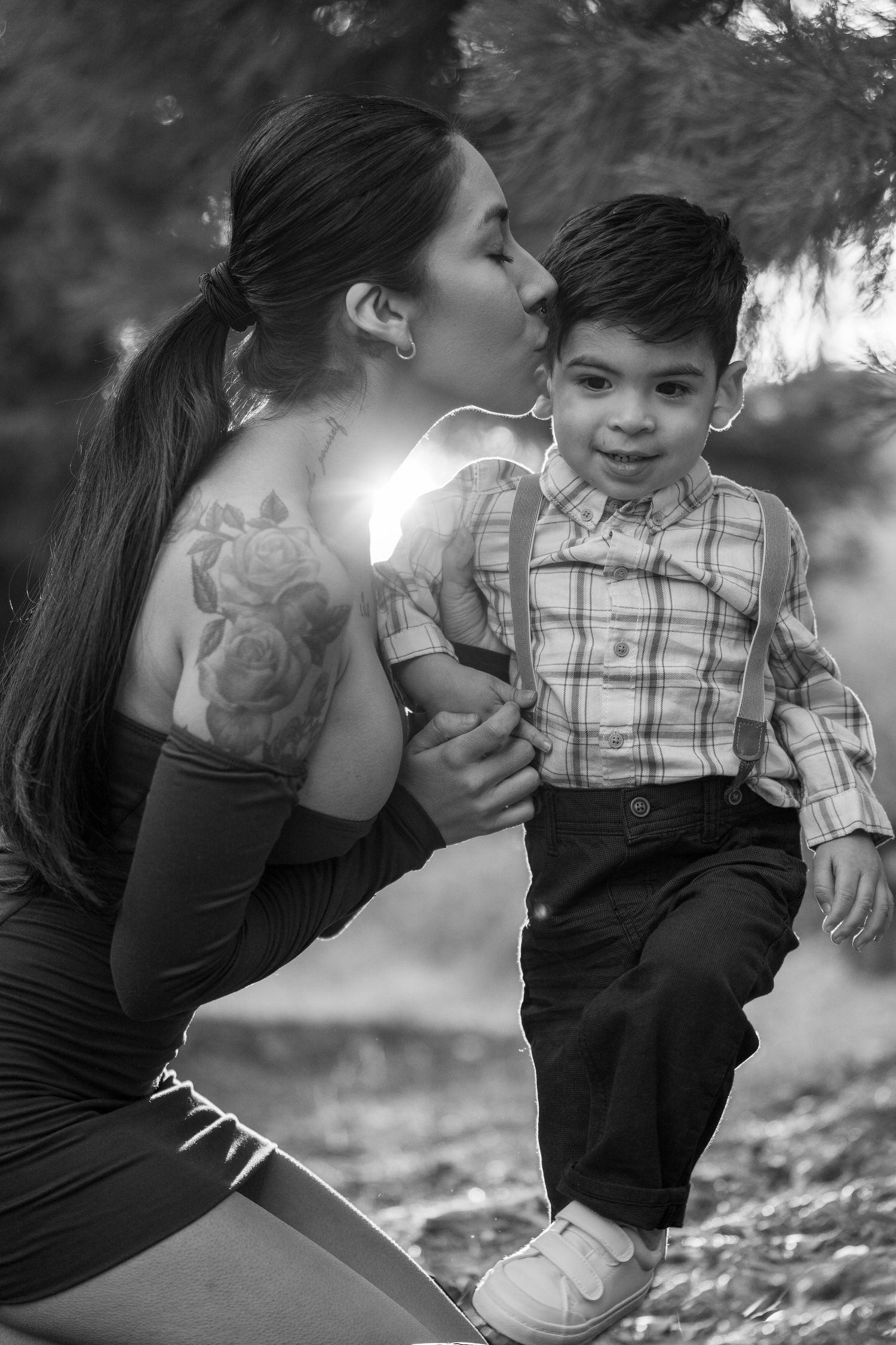 Black and white portrait of tender family moment outdoors among fallen leaves.