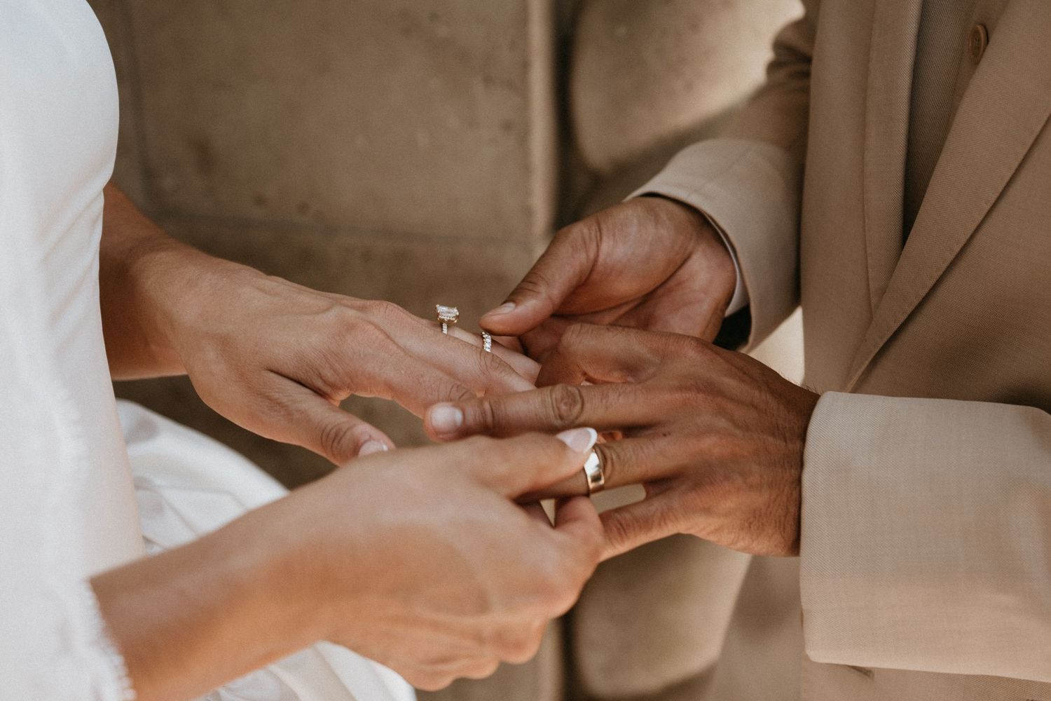 Close-up of hands exchanging wedding rings during marriage ceremony.