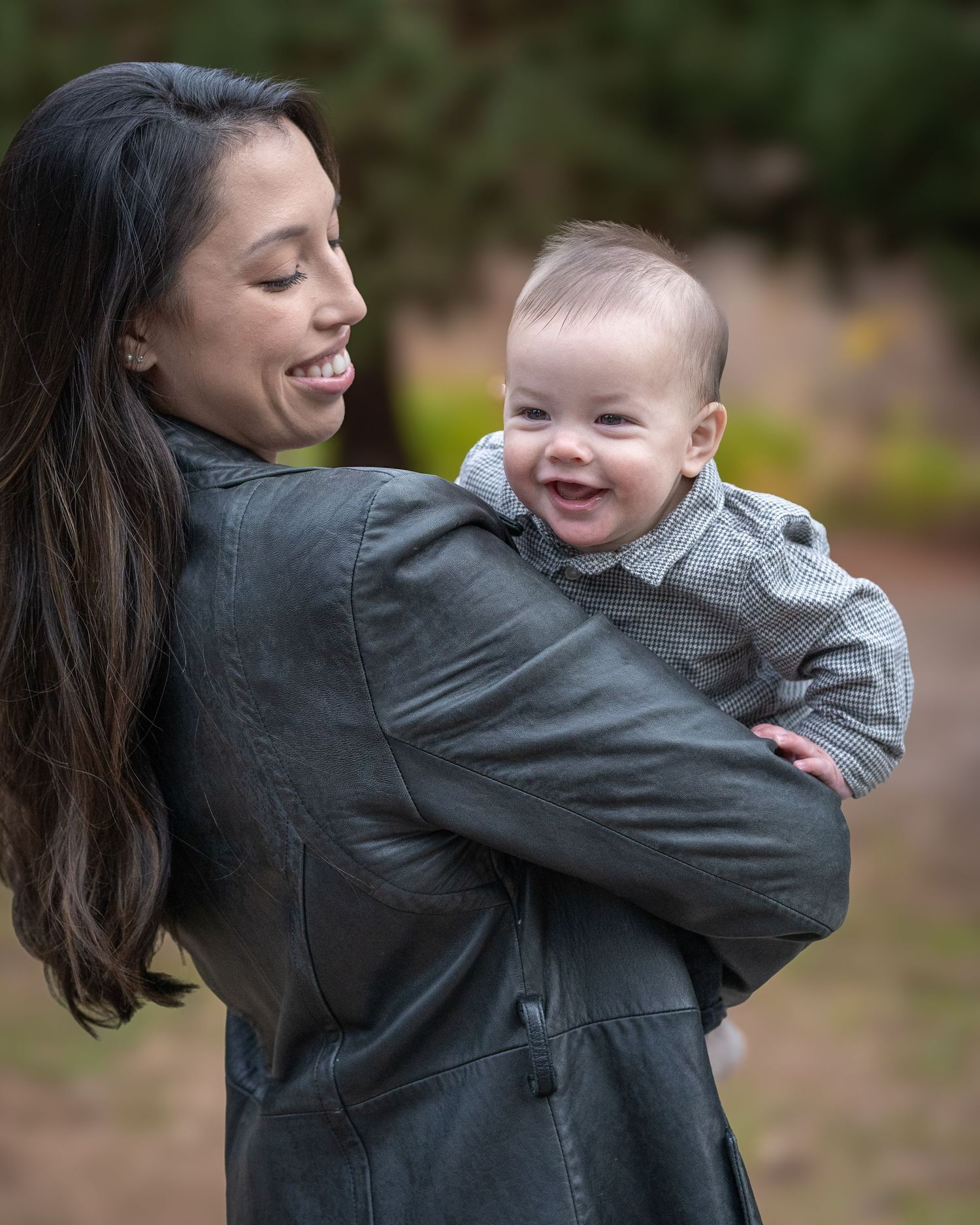 Candid moment of parent and baby sharing joyful laughter outdoors.