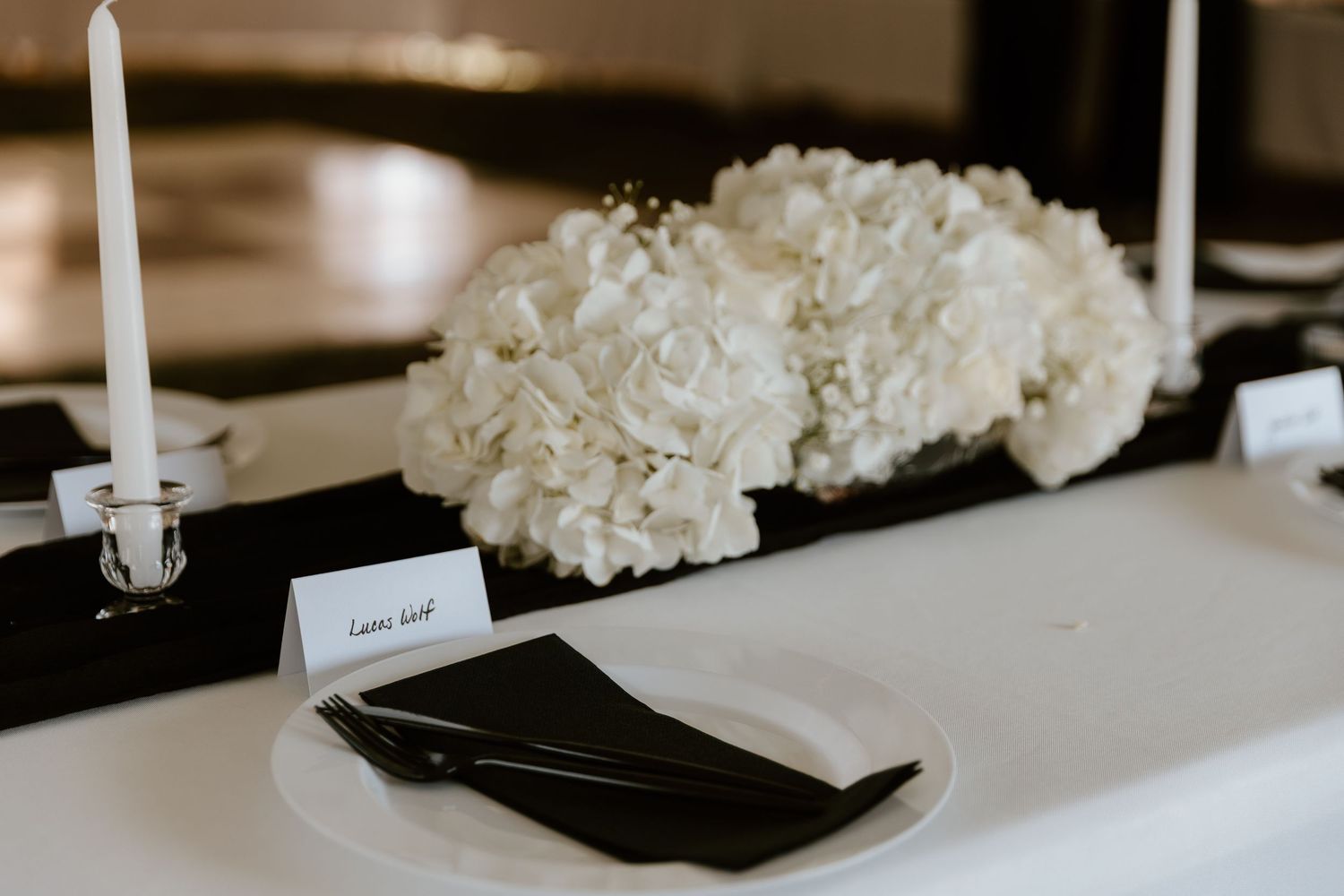 White flowers and candles create an elegant table setting at a wedding reception.