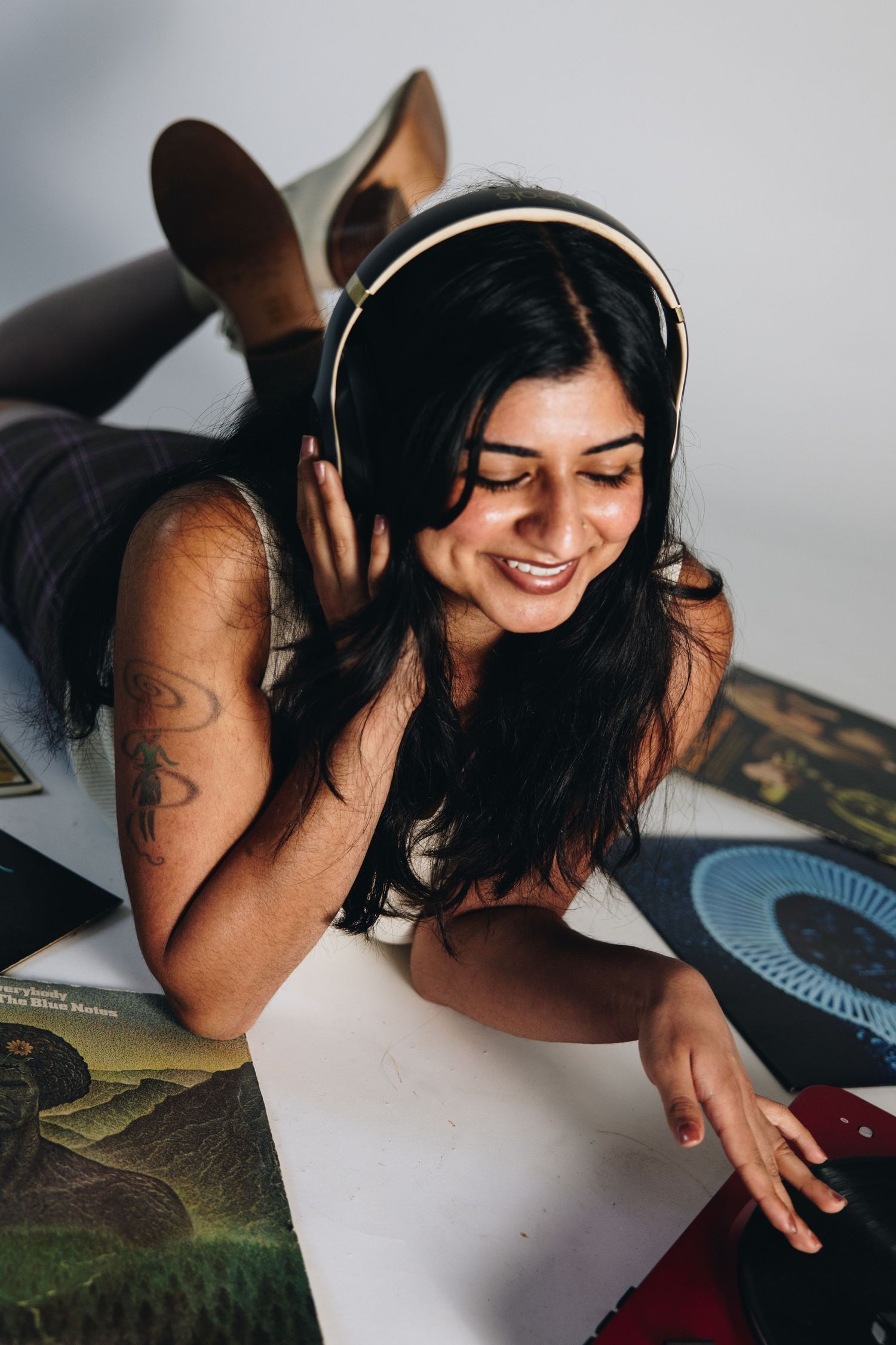Person lying on floor with headphones enjoying music surrounded by vinyl records.
