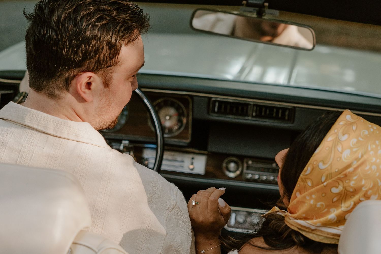Person in white shirt consulting map while sitting in vintage car interior.