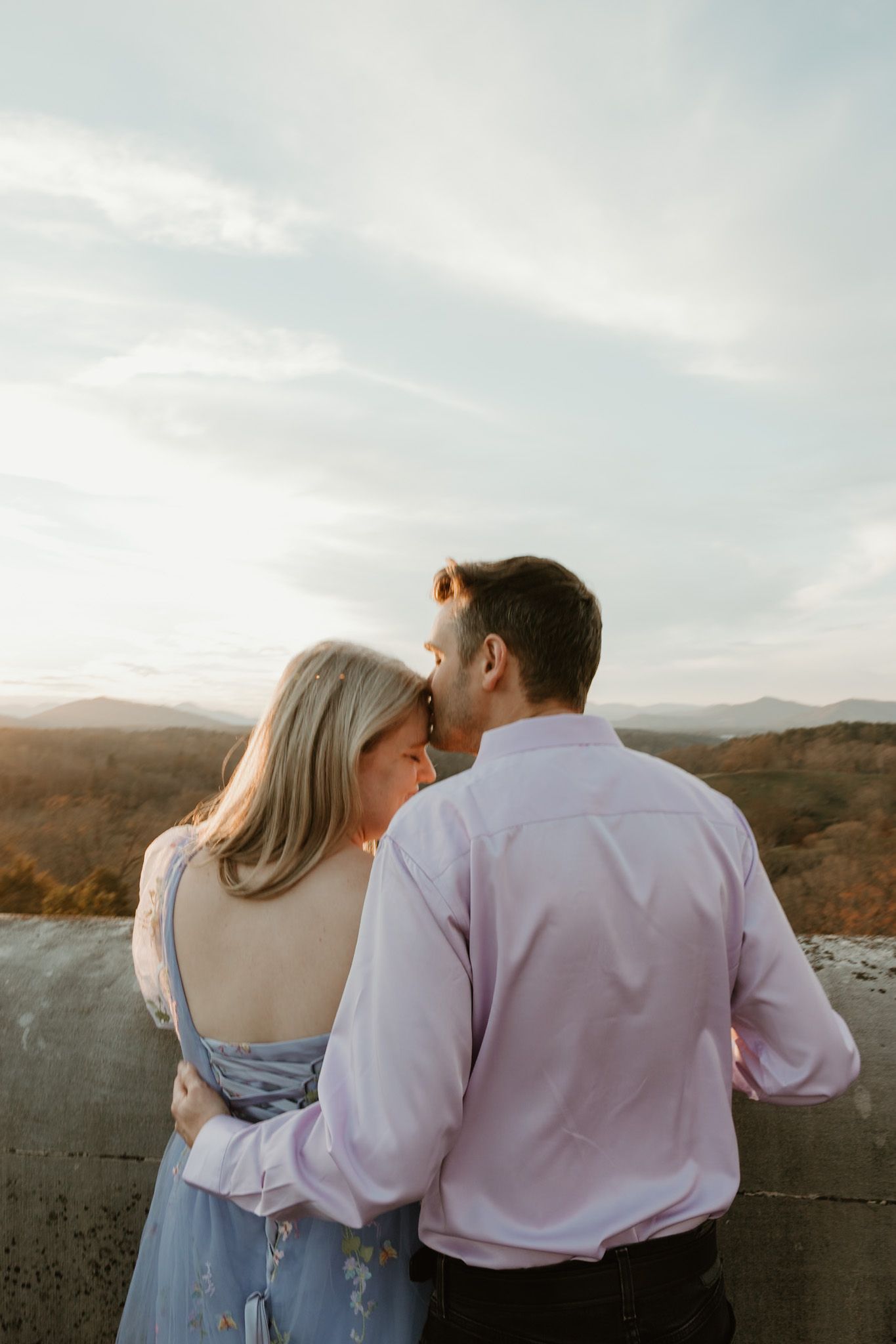 Romantic couple enjoying sunset views over mountain landscape from scenic overlook.