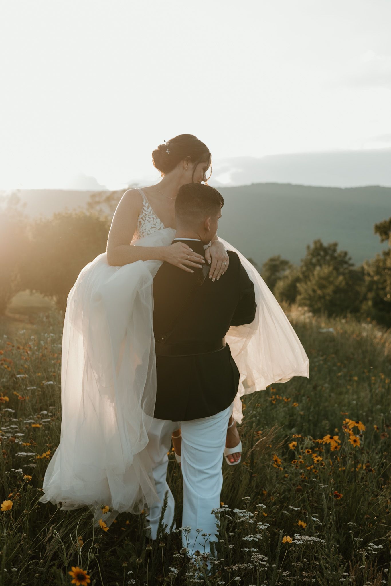 Sunset wedding photos in a field of wildflowers with mountain backdrop.
