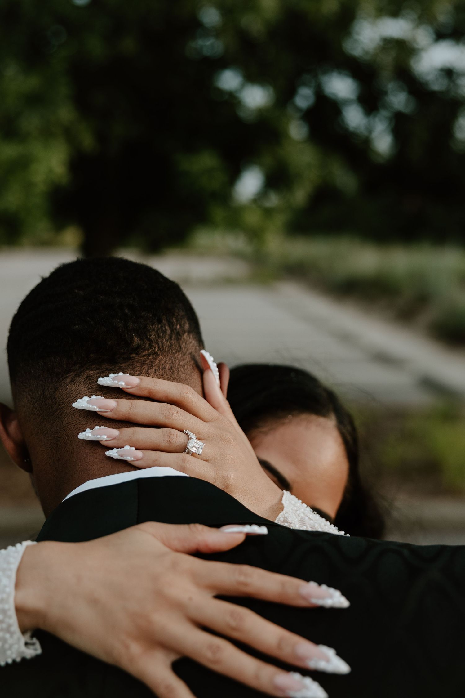 Close-up of hands with long decorated nails embracing during an intimate wedding moment.