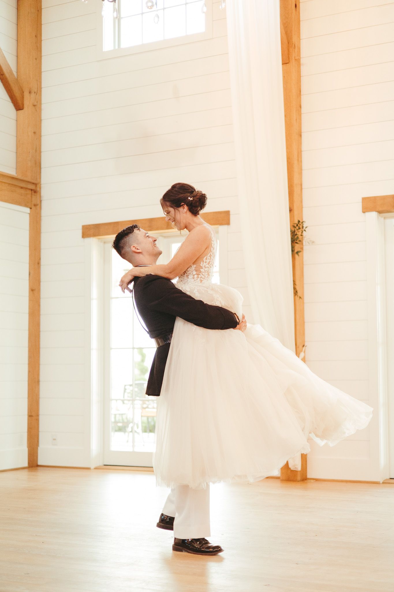 Couple dances in bright indoor venue with wooden beams and white walls.