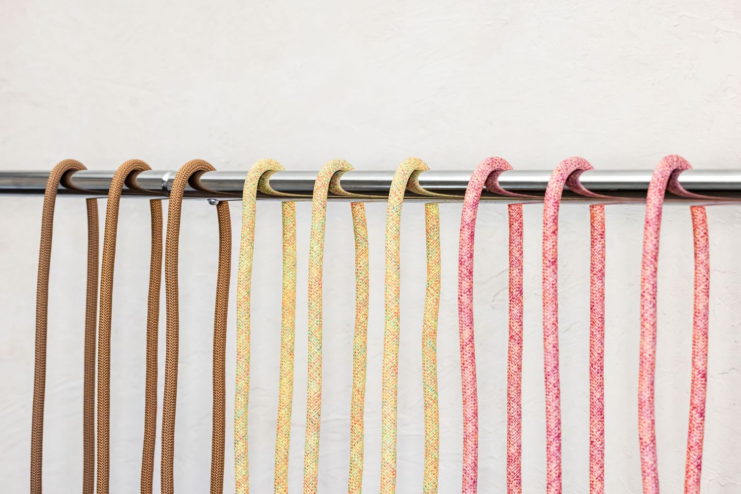Colorful knitting needles and yarn arranged in neat rows against a white background.