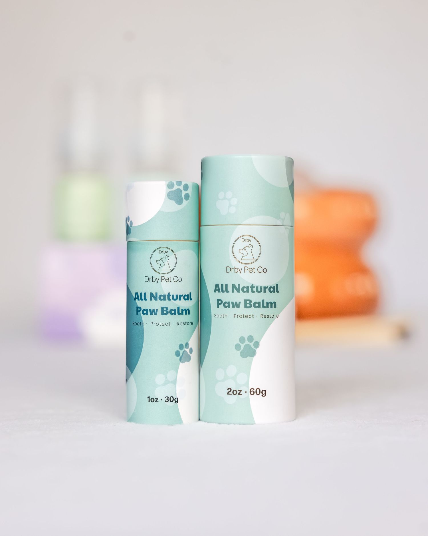 Two Dirty Pet Co All Natural Paw Balm sticks in mint green packaging, 1oz and 2oz sizes, on white surface.