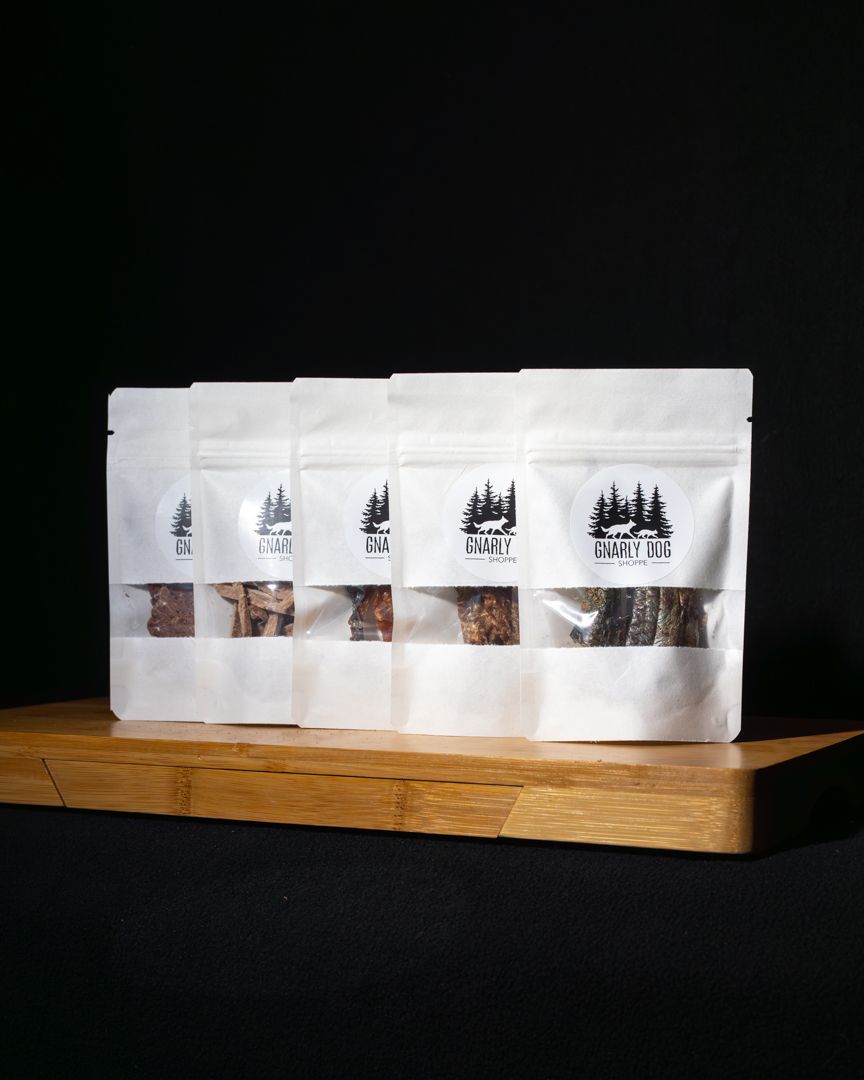 White coffee bags with forest tree designs arranged on wooden display stands against a dark background.