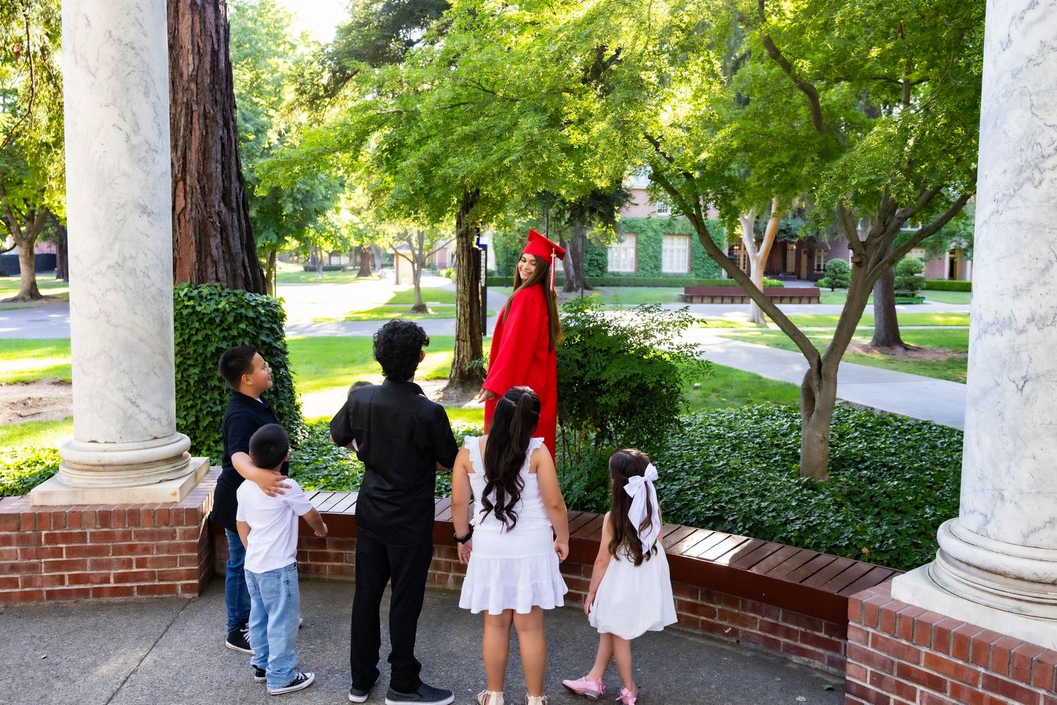 A series of connected images showing people walking and gathering near white columns and brick walls in an outdoor setting.