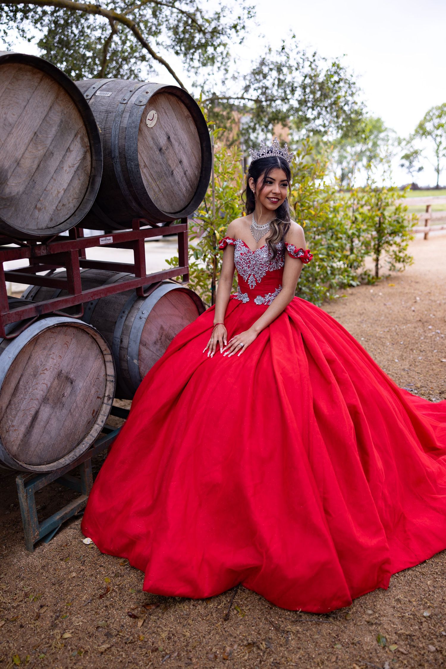 Stunning red quinceañera dress photographed at Winery among wine barrels in rustic setting in Lodi, California