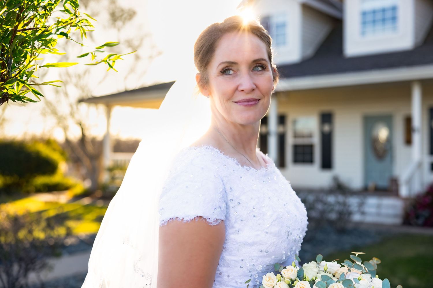Elegant bride glows in golden hour light outside charming farmhouse—captured by Lodi wedding photographer for timeless bridal portraits.