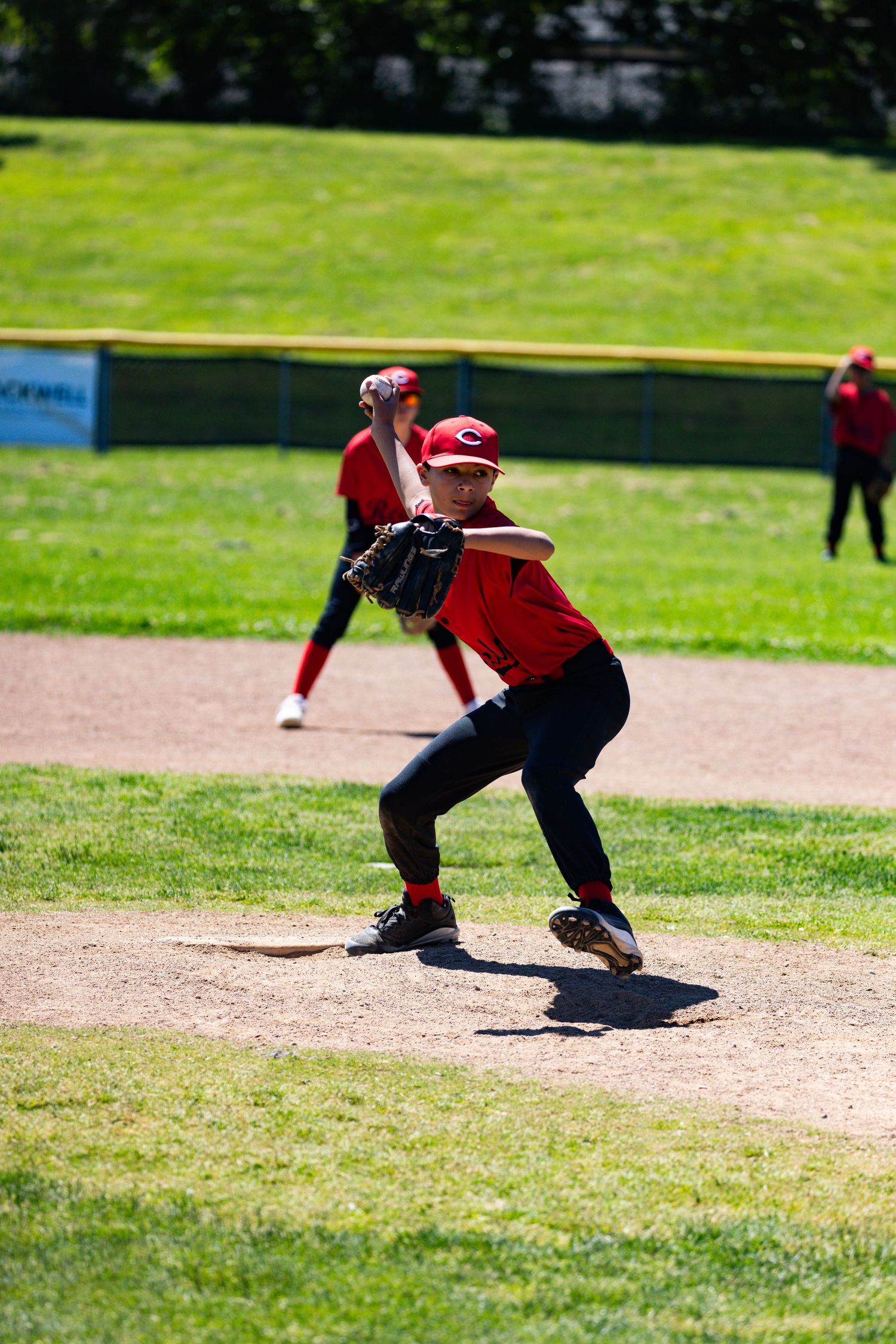 A baseball player in red uniform stands ready at bat on a sunny day.