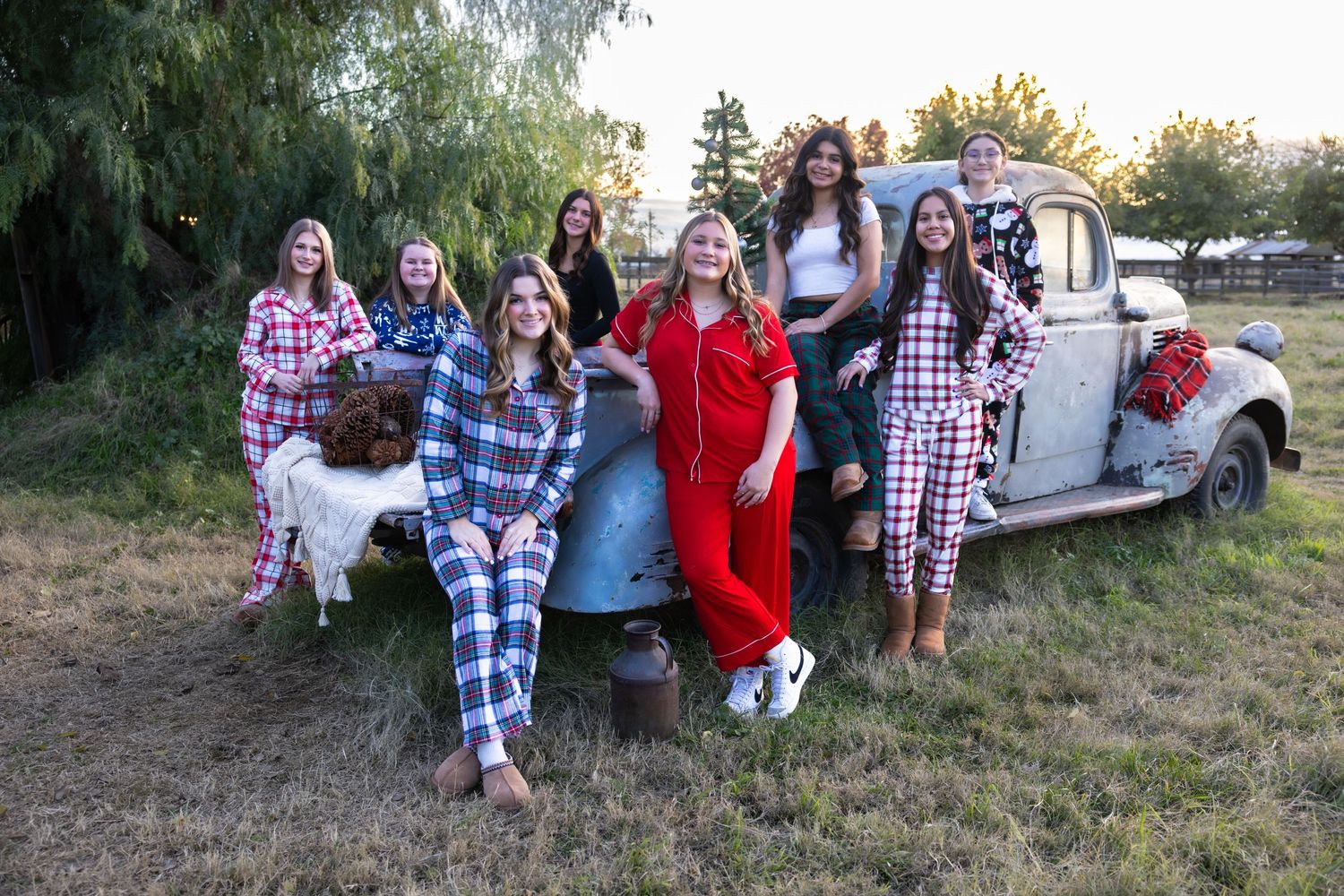 A group in matching pajamas poses with a vintage truck outdoors.