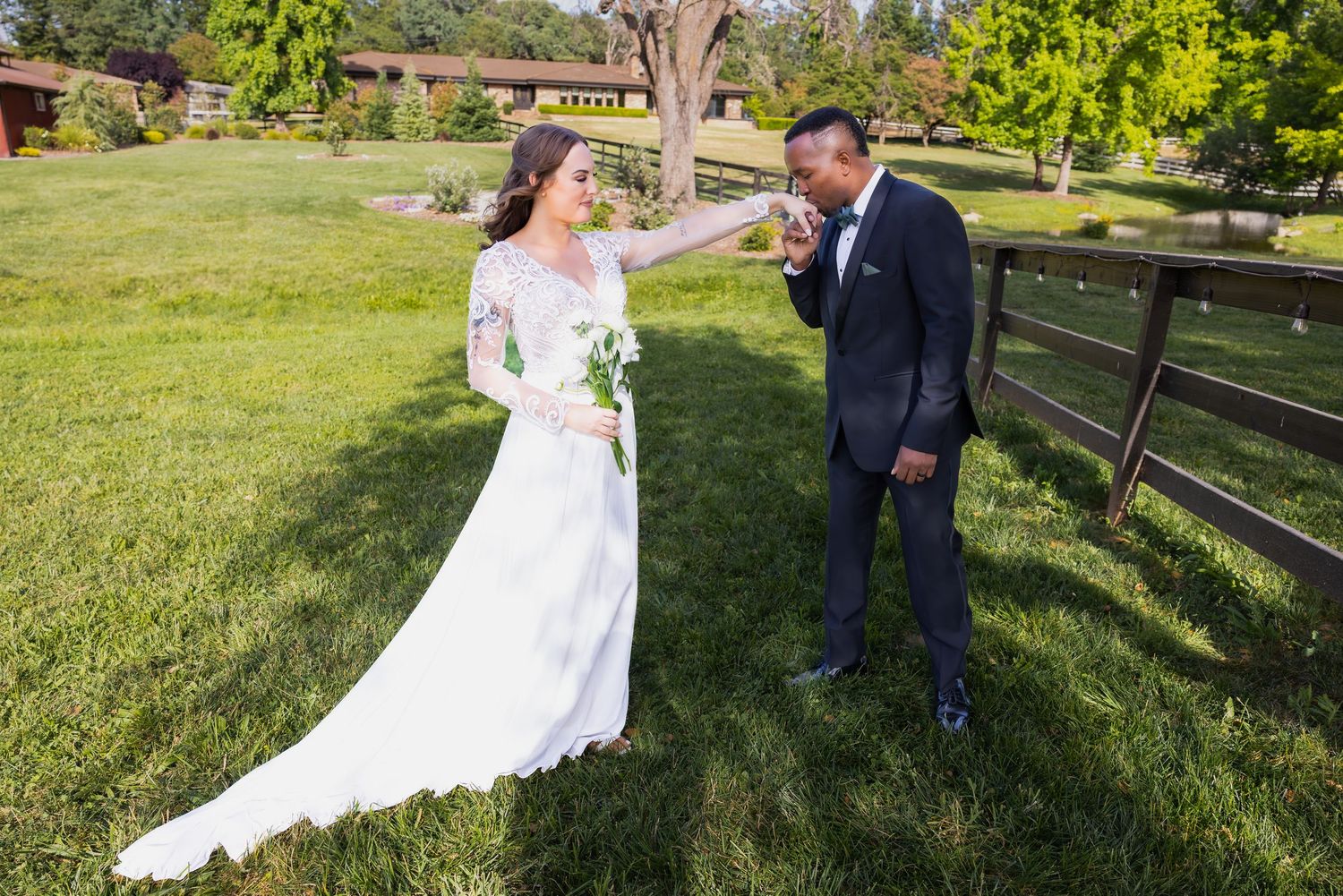 A couple enjoying a candid moment together on their wedding day in a scenic outdoor setting with wooden fences.