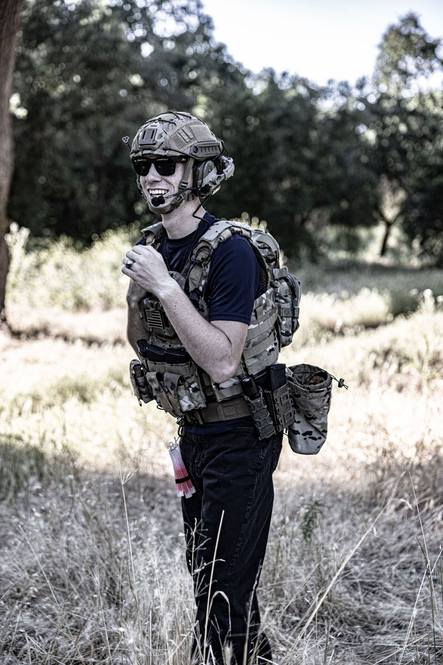 Tactical gear-equipped person with helmet and backpack standing in dry grassland in Stockton.