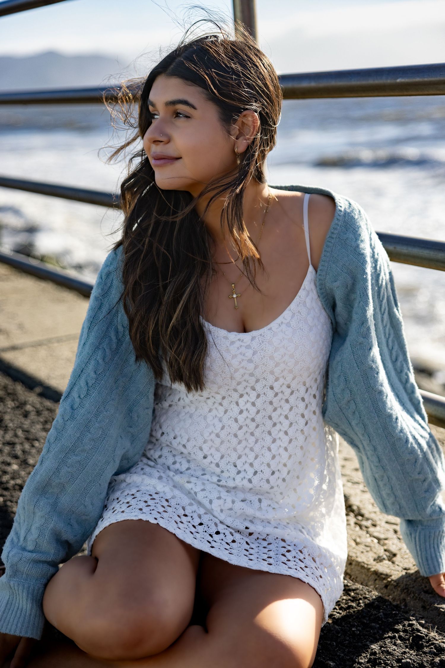 A thoughtful moment captured at the beach with a white crochet top and blue cardigan against an ocean backdrop, Bay Area, Pacifca.