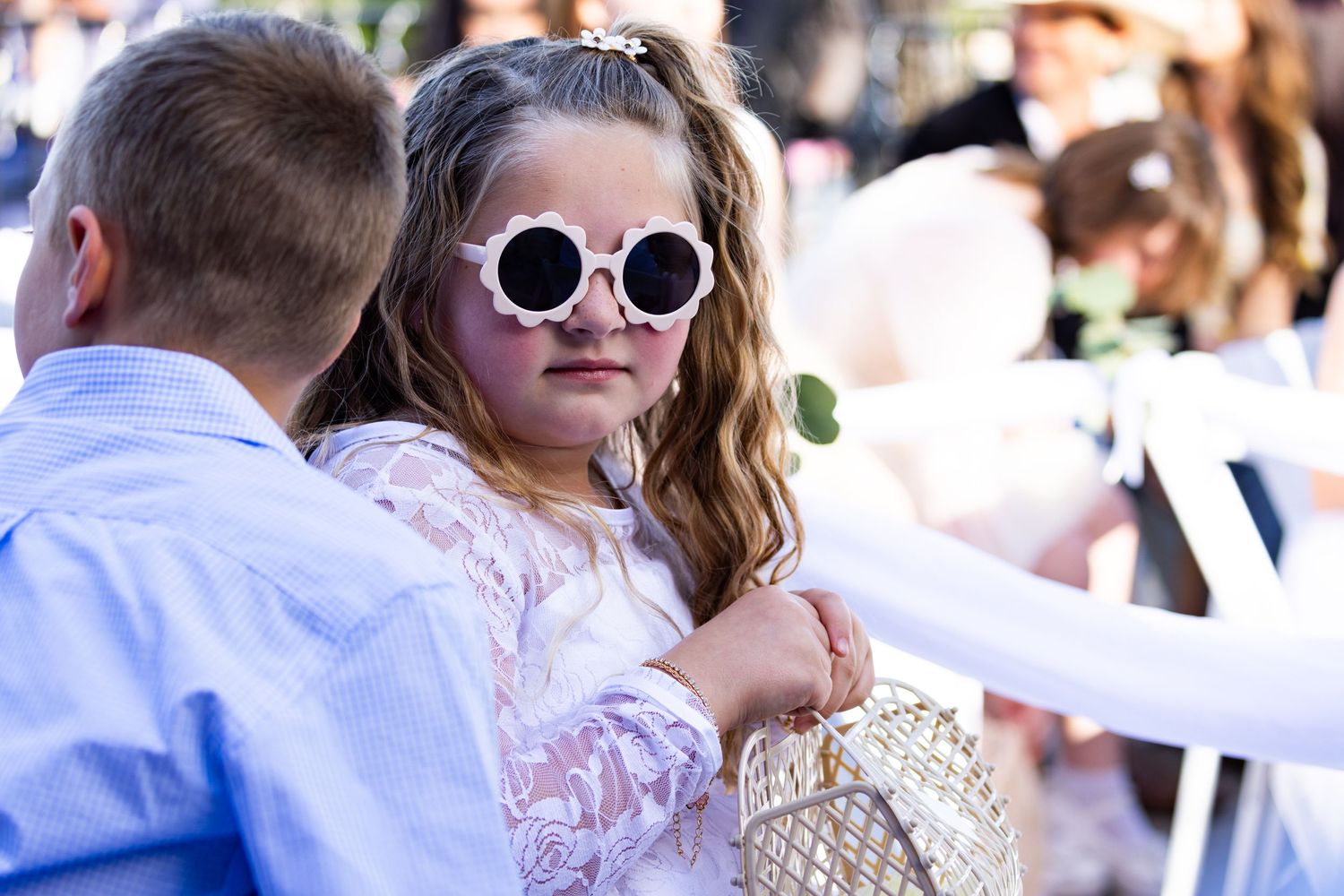 Stylish party-goer wearing pink dress and retro round sunglasses at outdoor celebration.