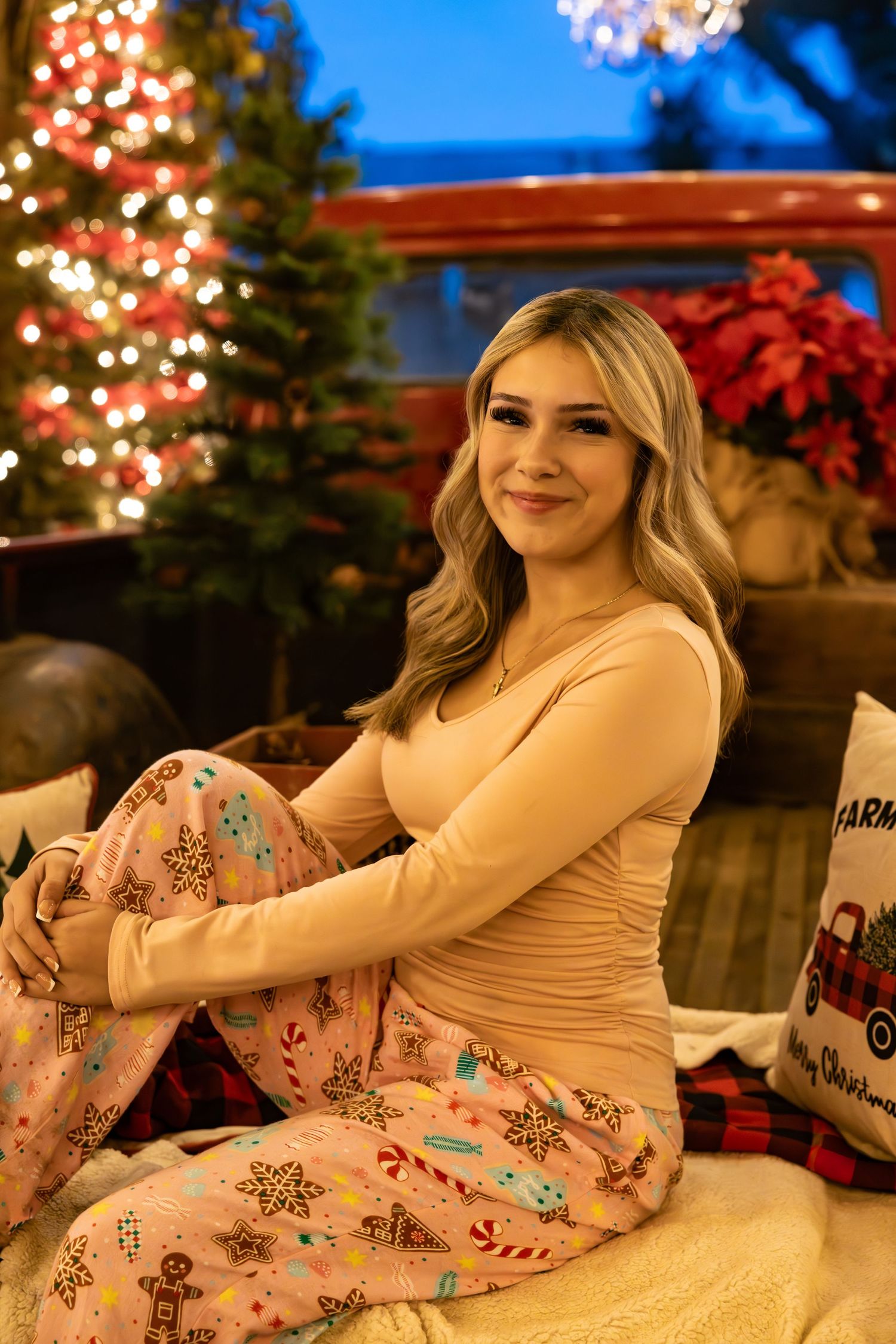 Person relaxing on couch wearing pink patterned pajamas with Christmas tree and holiday decorations in background.