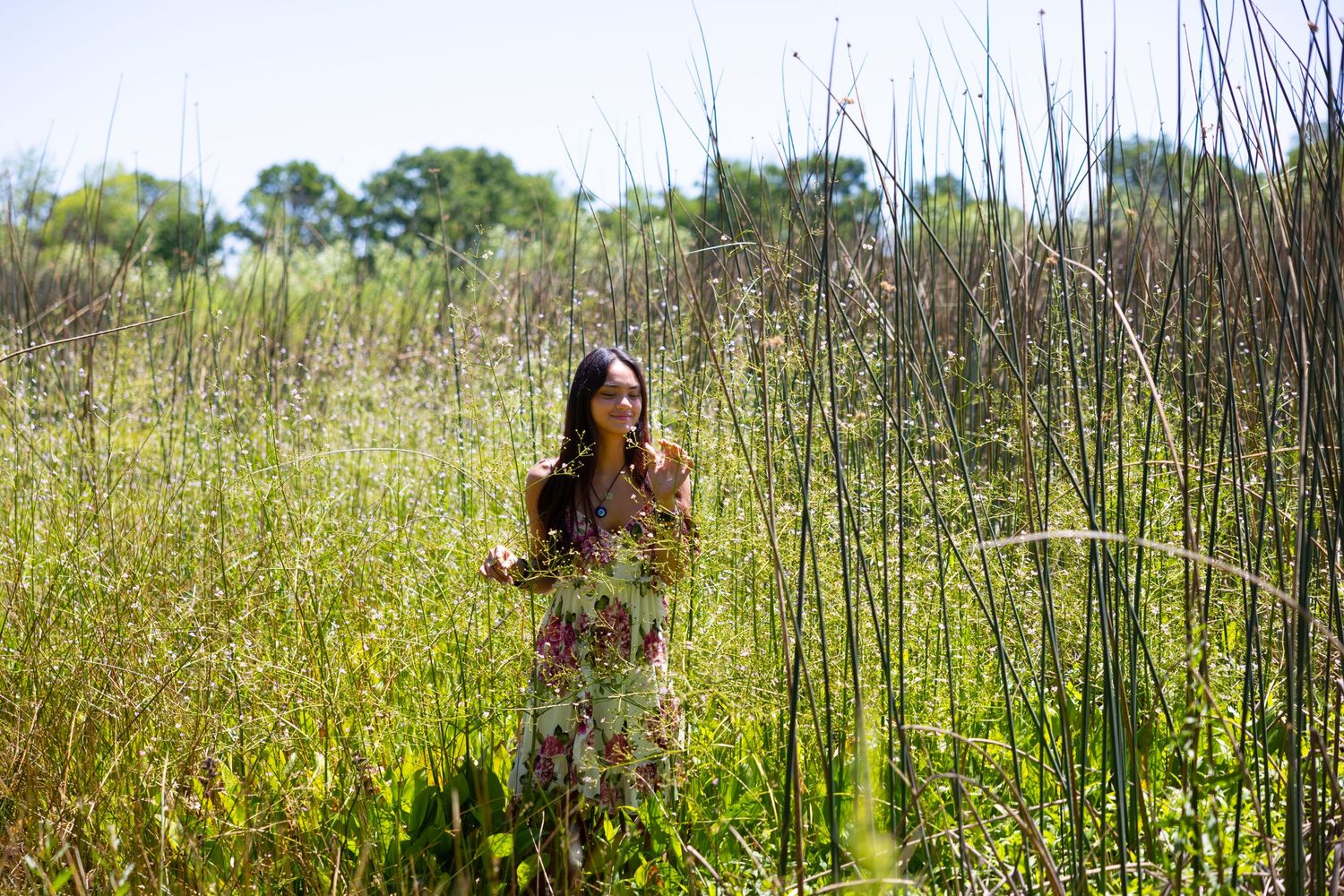 Senior girl in floral dress standing in tall spring grass at Lodi Lake — perfect light, natural beauty, and timeless senior portrait vibes.
