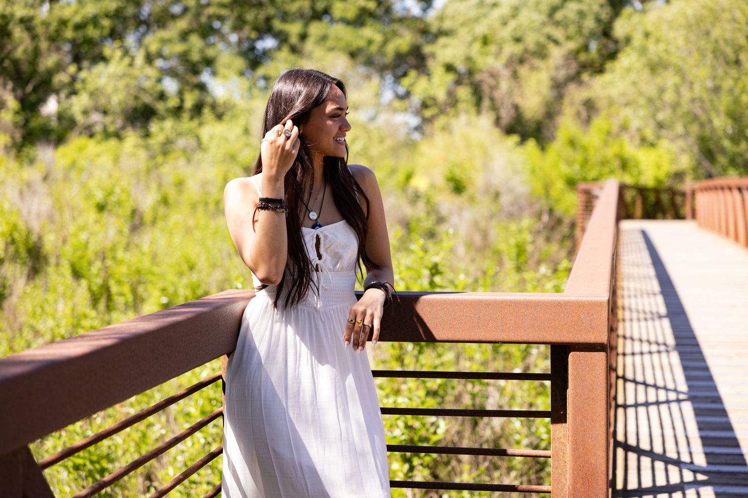 A white sundress complements natural scenery on a wooden bridge overlook in Galt, Consumes River Preserve, Sacramento for a senior session.