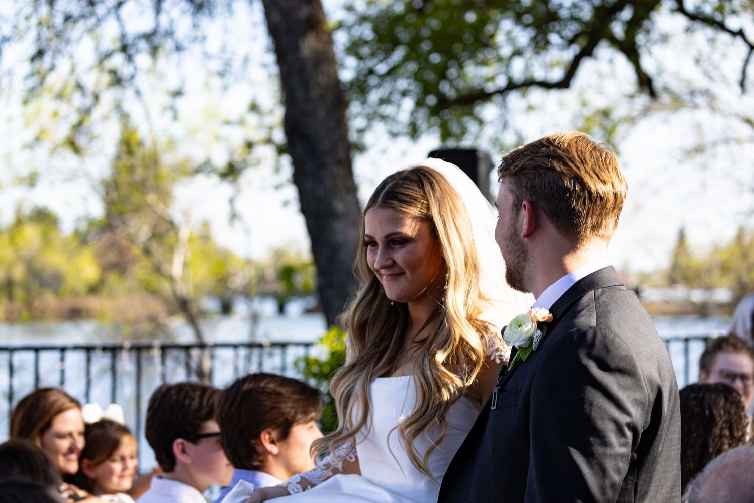 Romantic outdoor wedding in Chico, CA captured by Katie Malinda. First kiss under a floral arch—timeless, elegant, unforgettable moment.