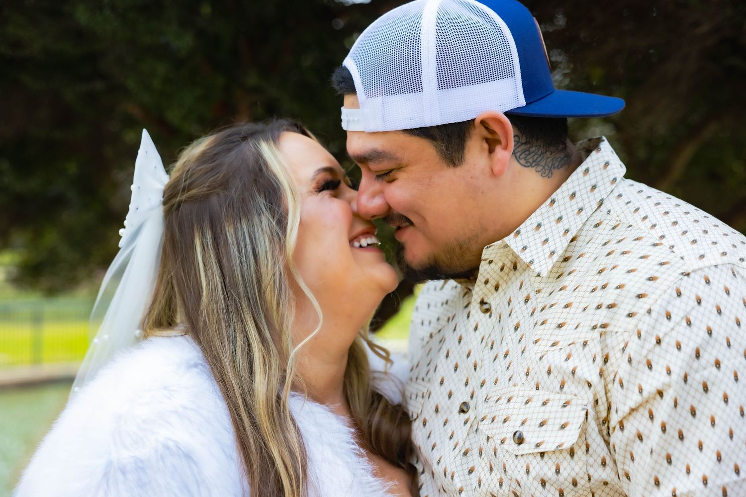 Intimate moment between newlyweds in casual wedding attire outdoors in Stockton by lake, kissing.