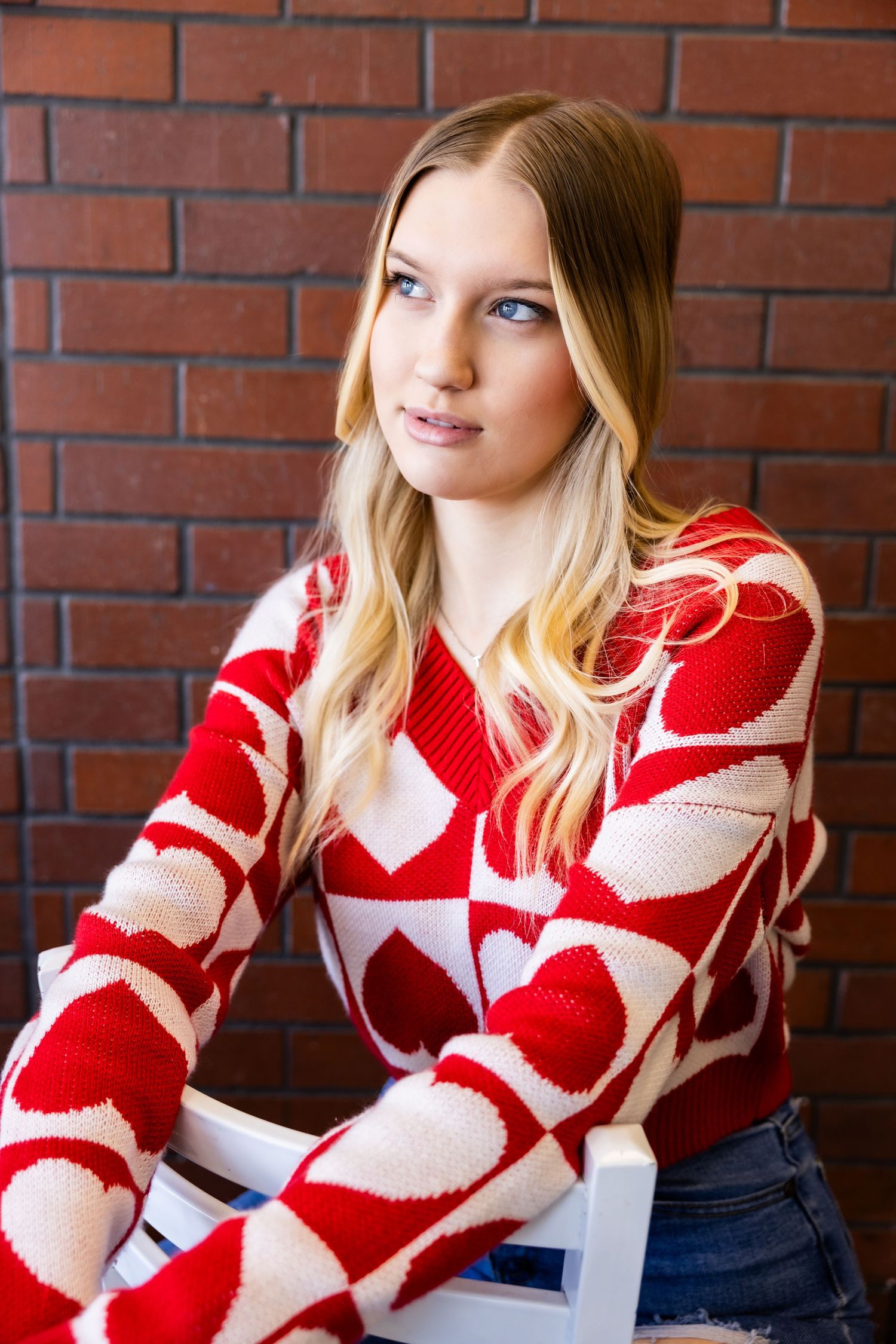 Model wearing red and white patterned sweater poses against brick wall background in Elk Grove.