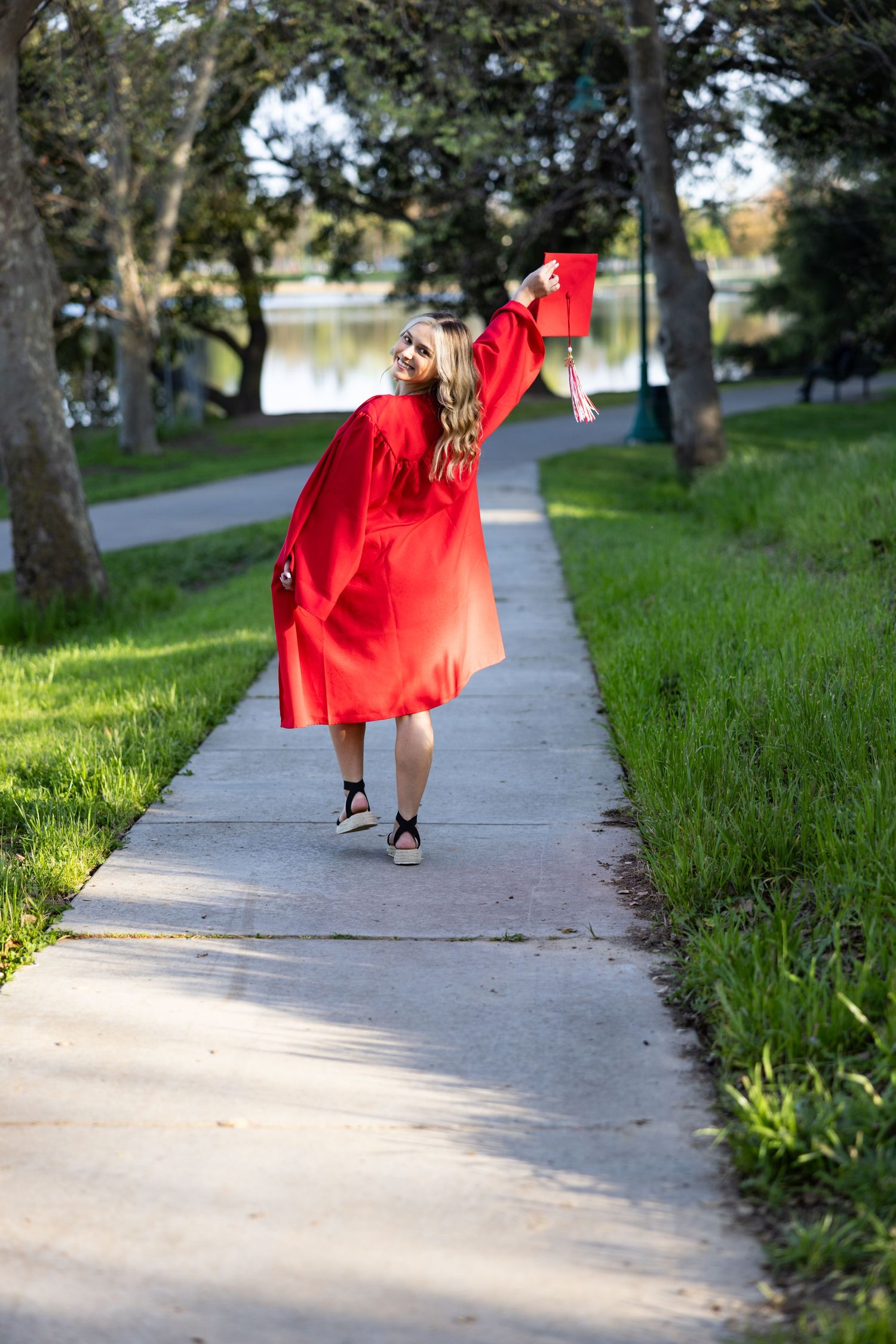 Katie Malinda, senior photographer, girl at Lodi Lake in cap and gown, celebrating true happiness, outside in nature.