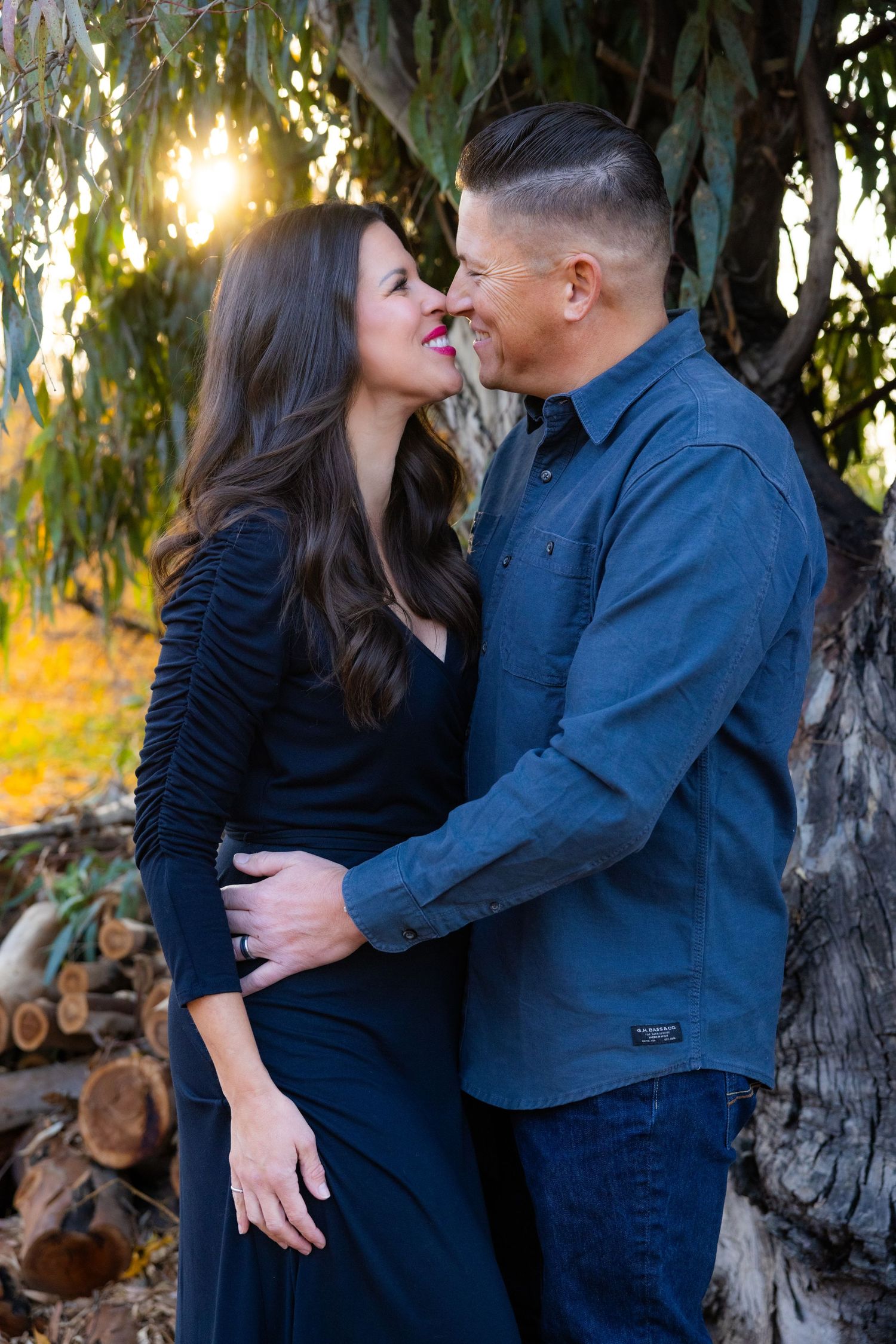 Romantic couple sharing intimate moment against eucalyptus tree at sunset.