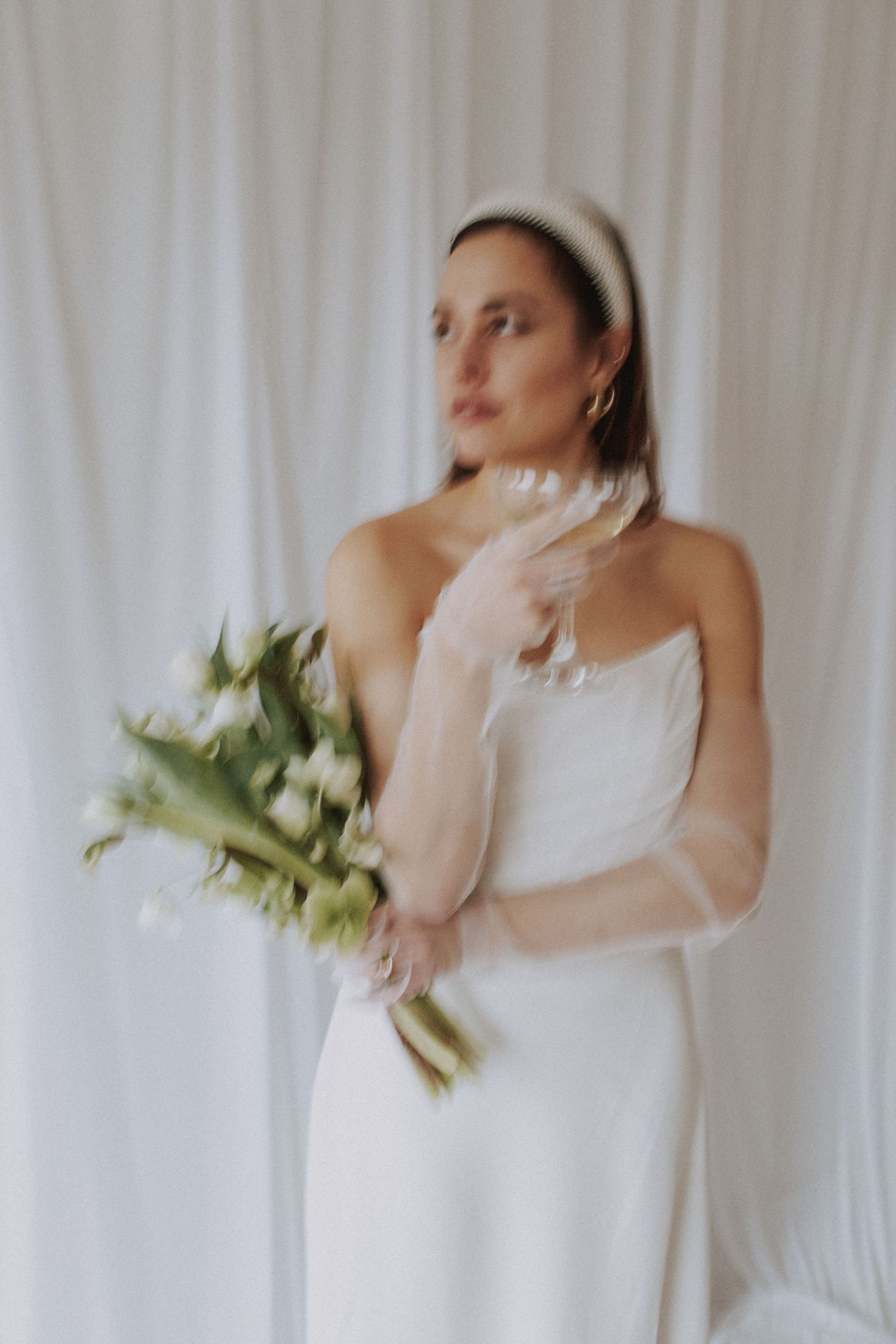 Ethereal bridal portraits with white flowers against light curtain background.