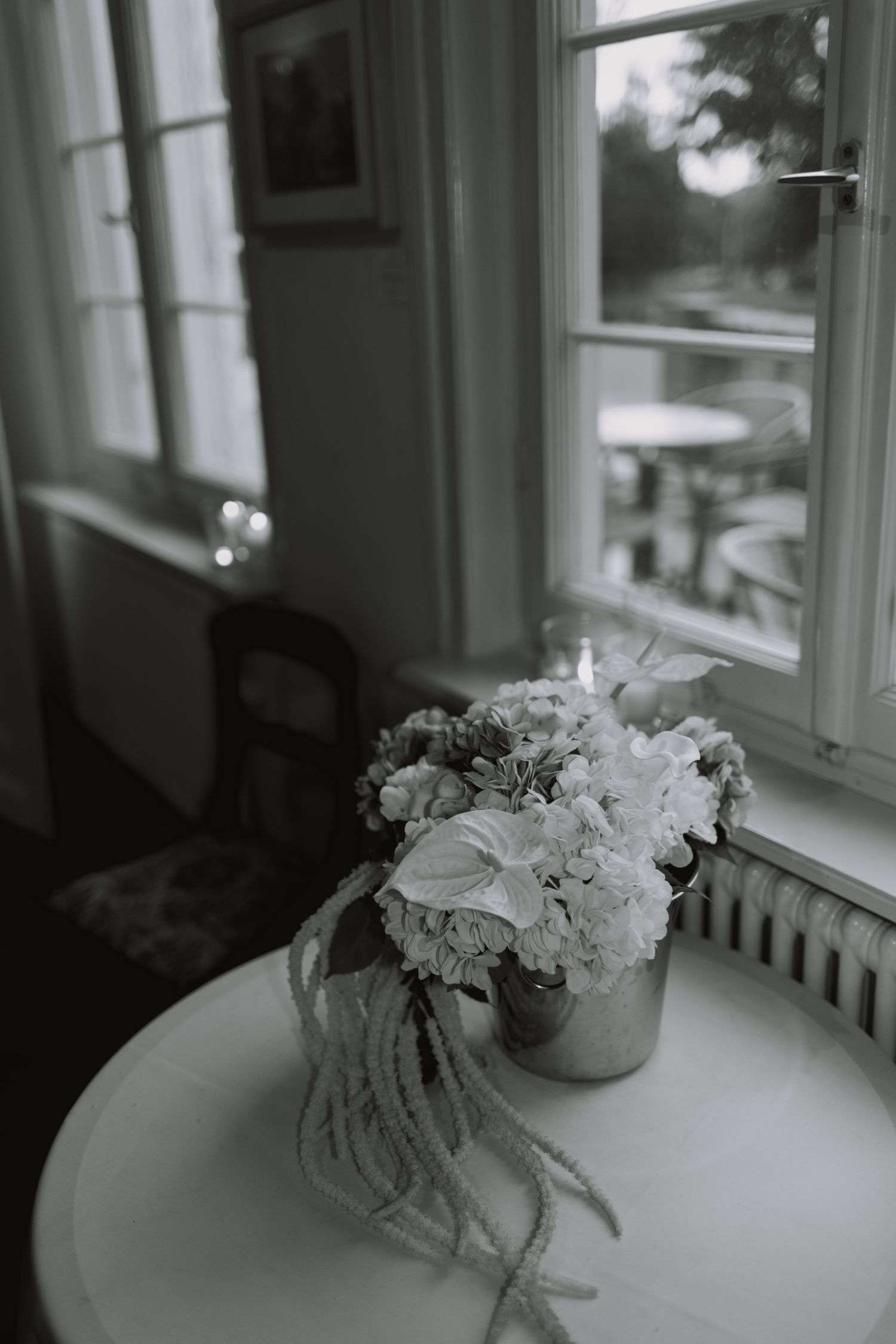 Delicate white floral arrangements placed near sunlit windows in a wedding venue.