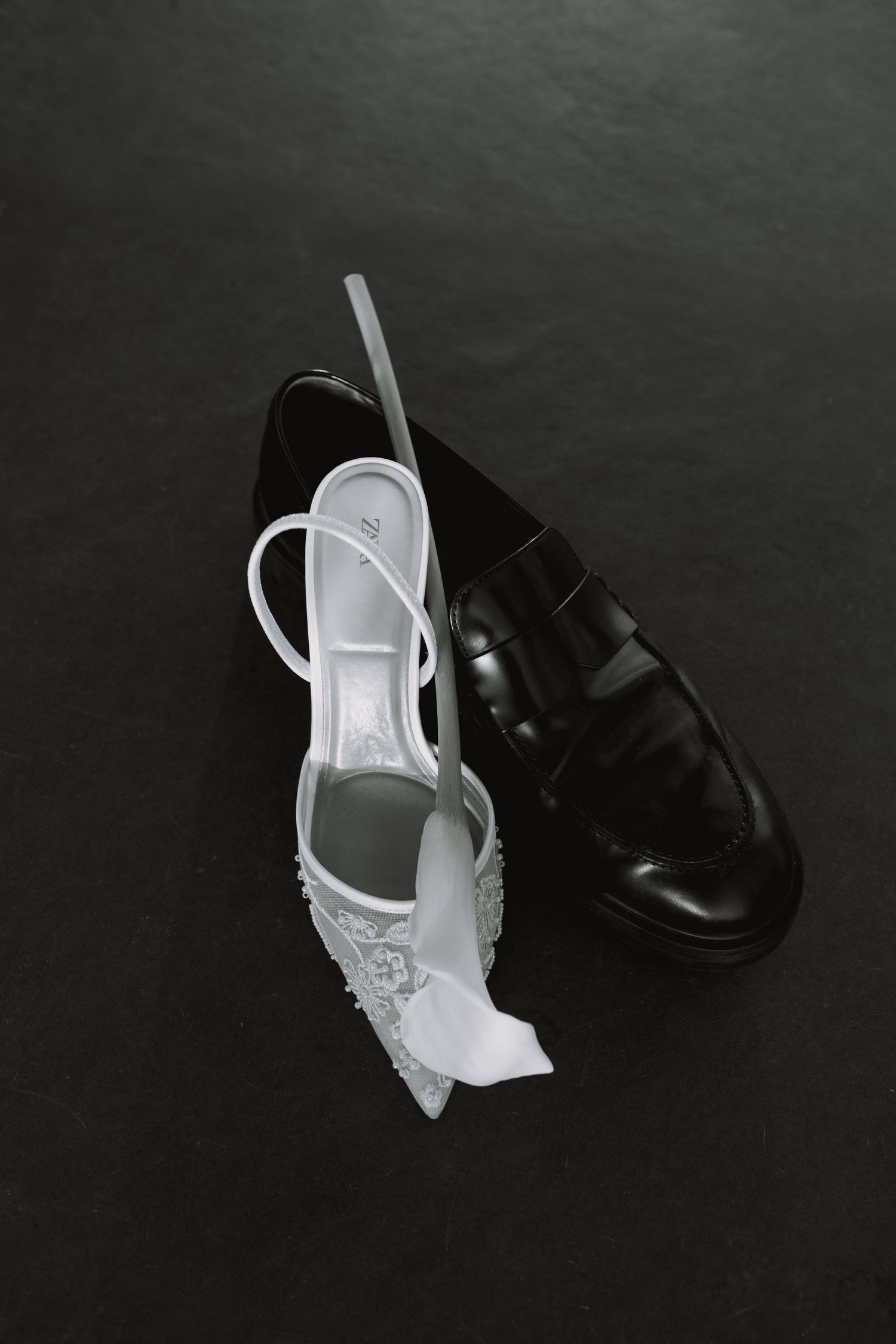 Black and white formal wedding shoes displayed on dark background.