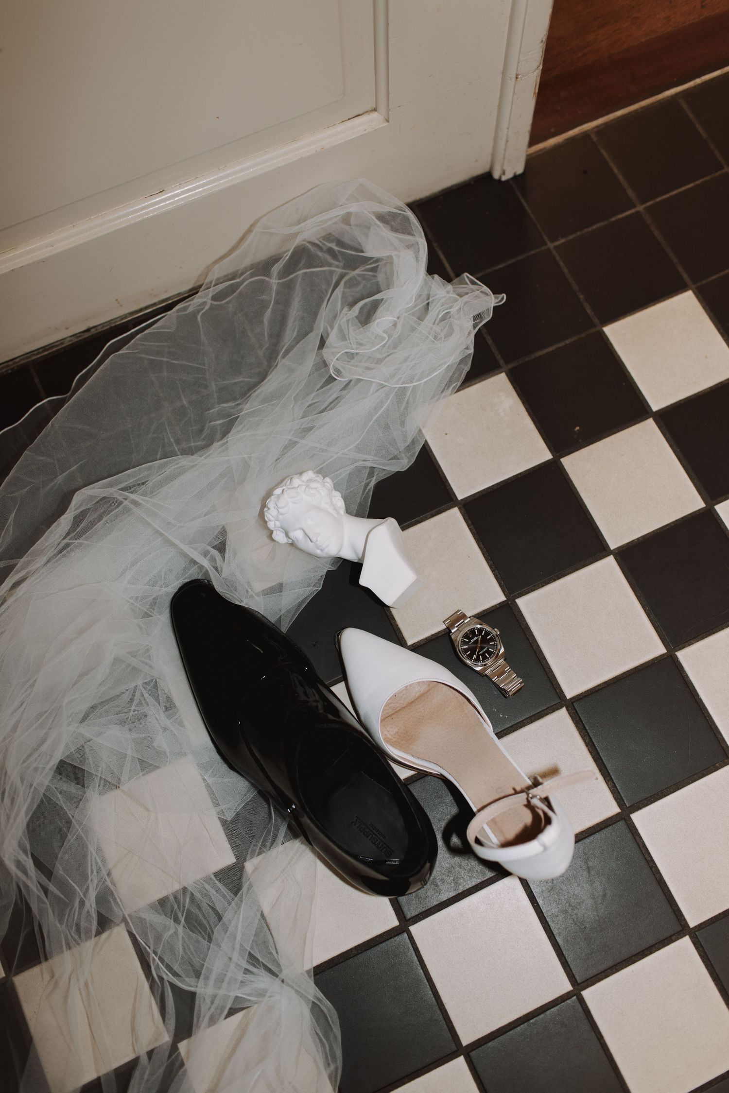 Wedding accessories arranged on black and white checkered floor.