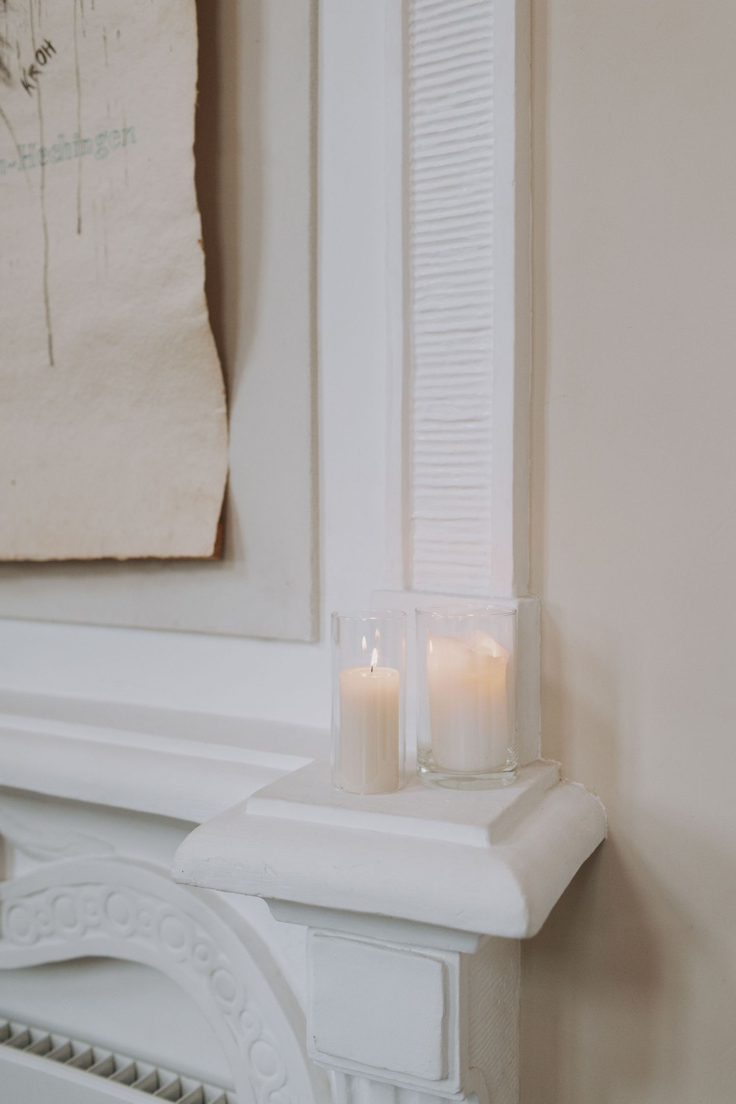 White fireplace mantel with glowing candles and classic architectural details.