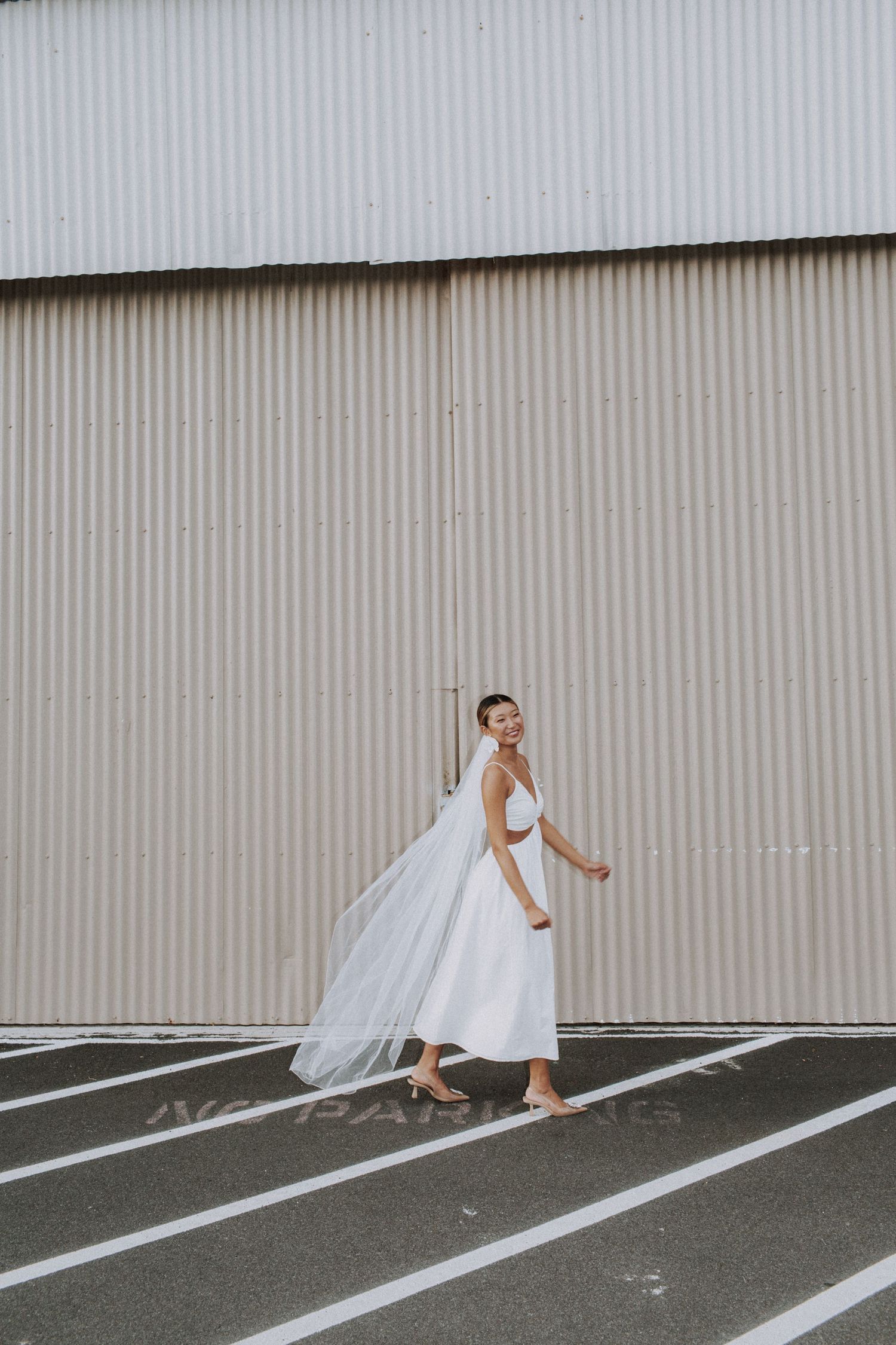 Person in flowing white dress creating dynamic movement against industrial wall.