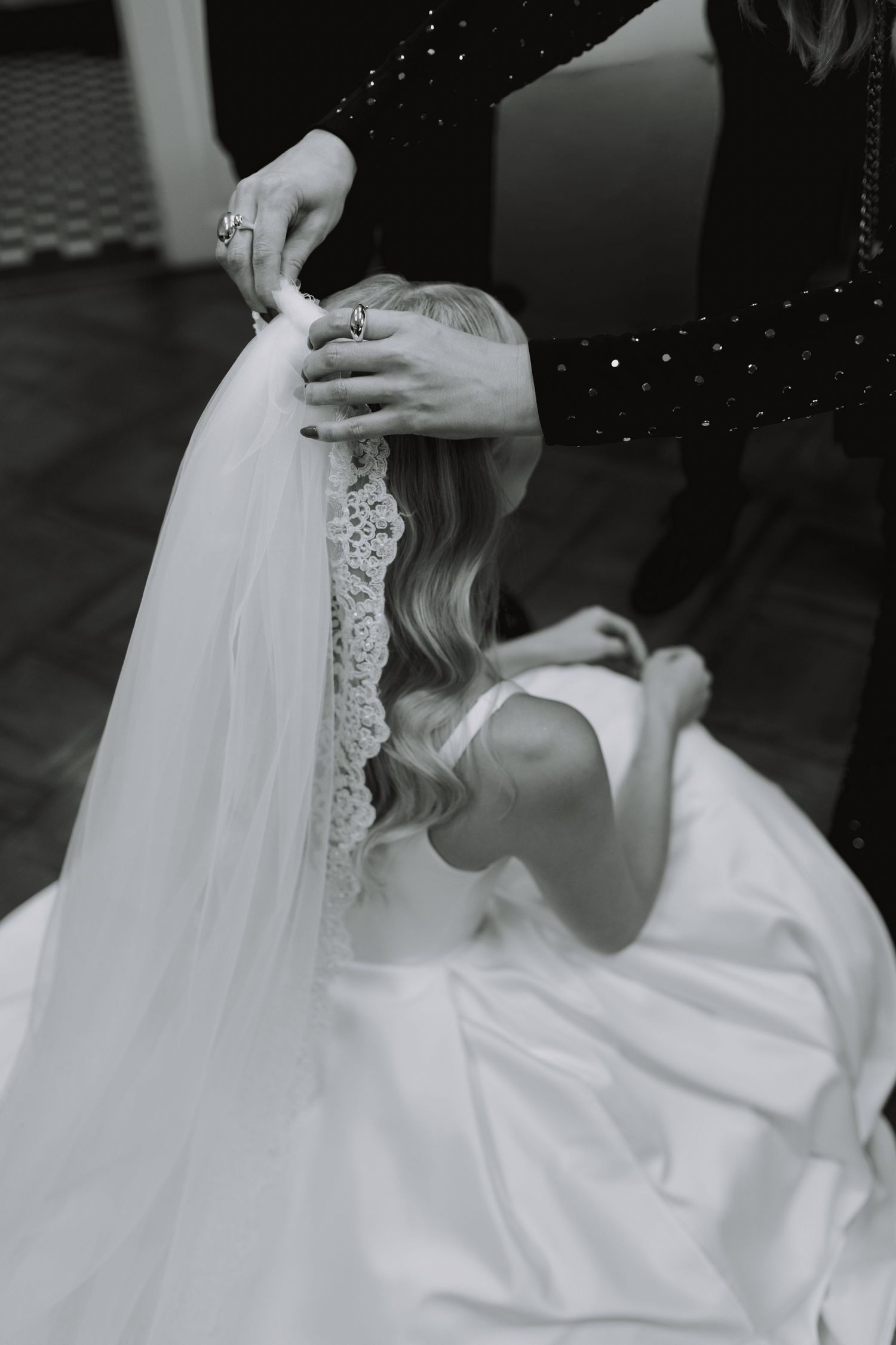 Close-up details of white wedding dress and veil in black and white.